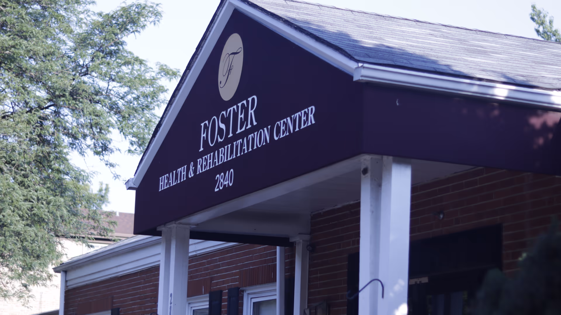 Front view of Foster Health & Rehabilitation Center signage on brick building