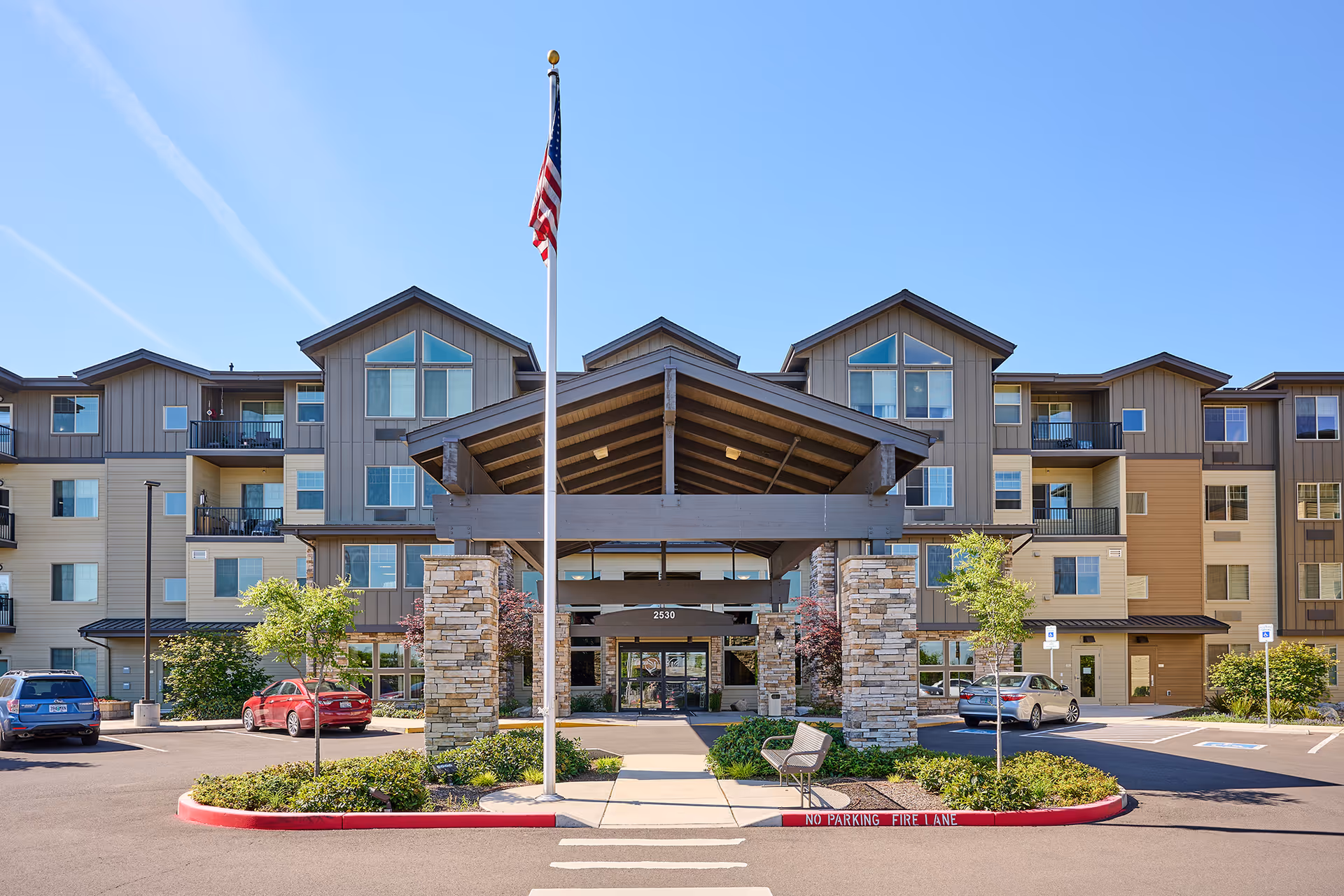 Exterior view of Bonaventure of Medford entrance with flag and parking