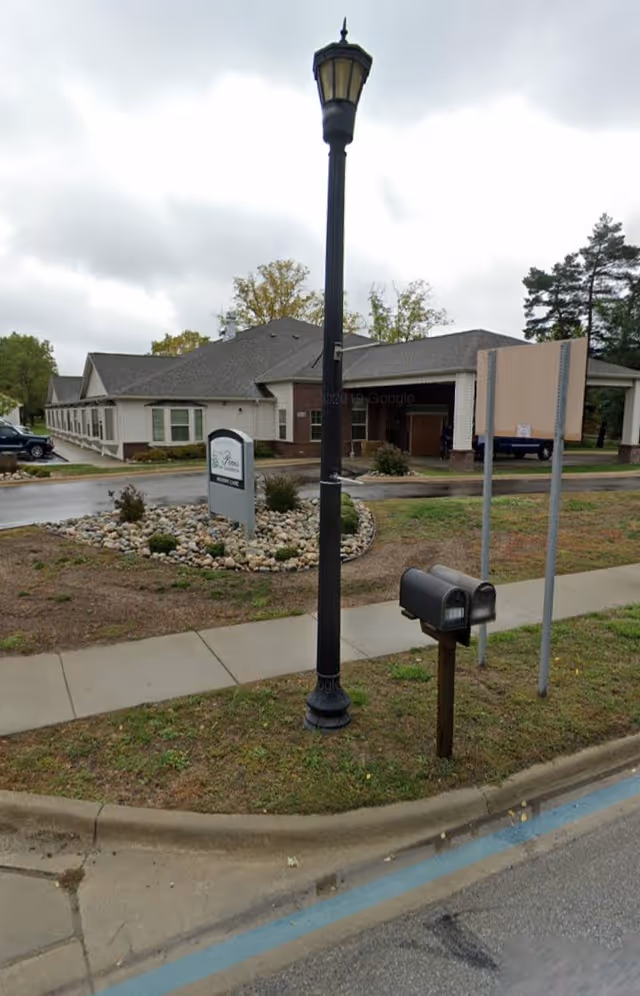 Front view of The Pines of Goodrich with lamppost, sign, and landscaped entrance.