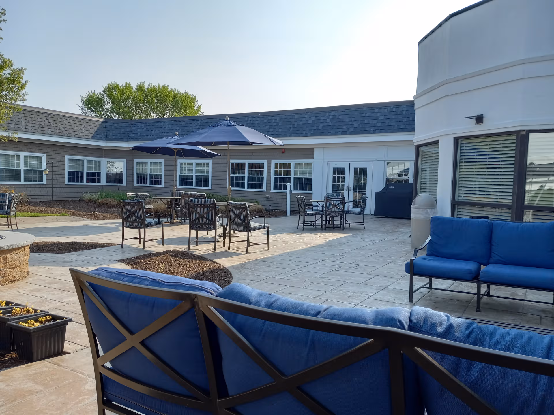 Outdoor courtyard patio with blue cushioned seating, umbrellas, and tables.