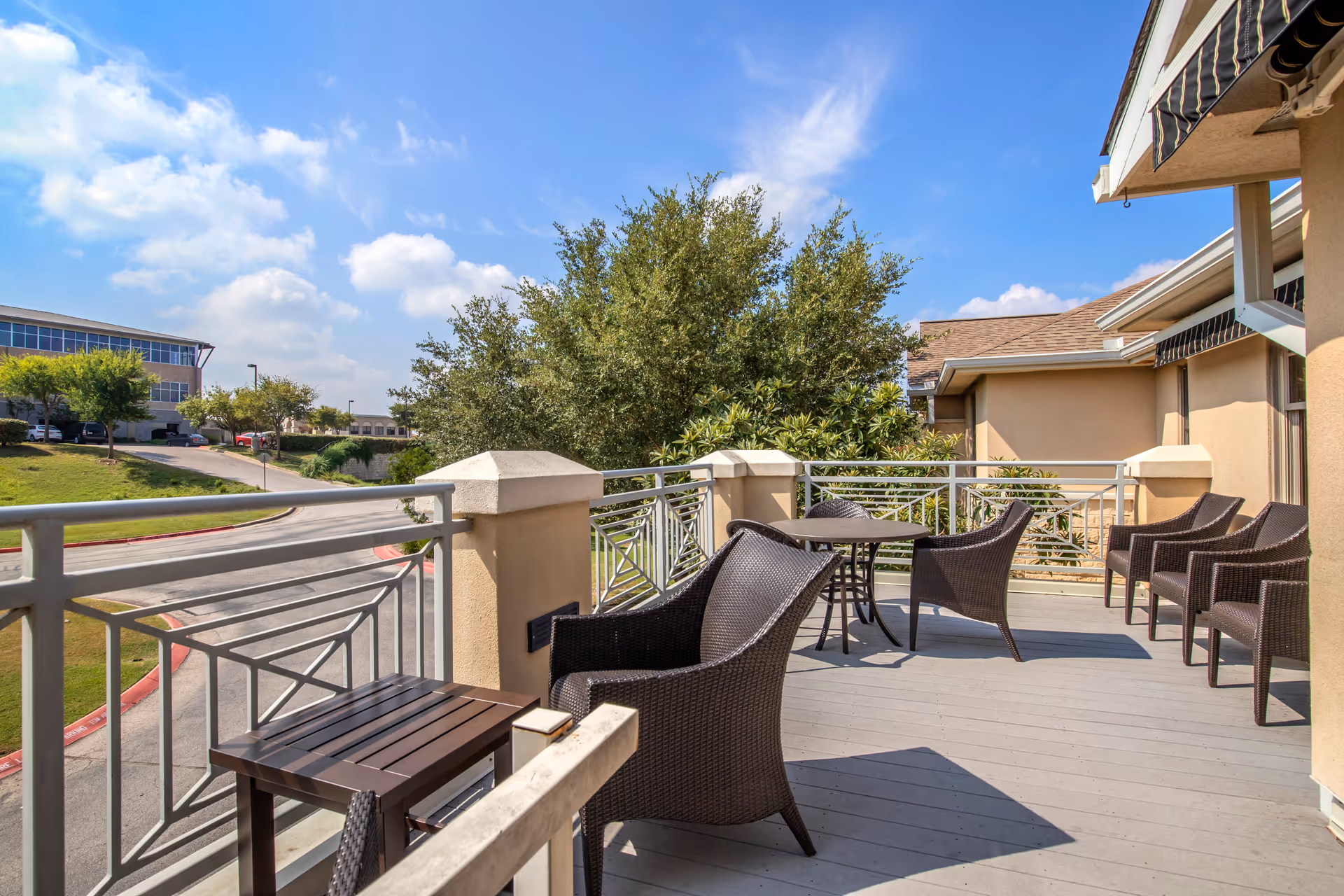 Outdoor terrace with wicker chairs and tables under a bright blue sky.