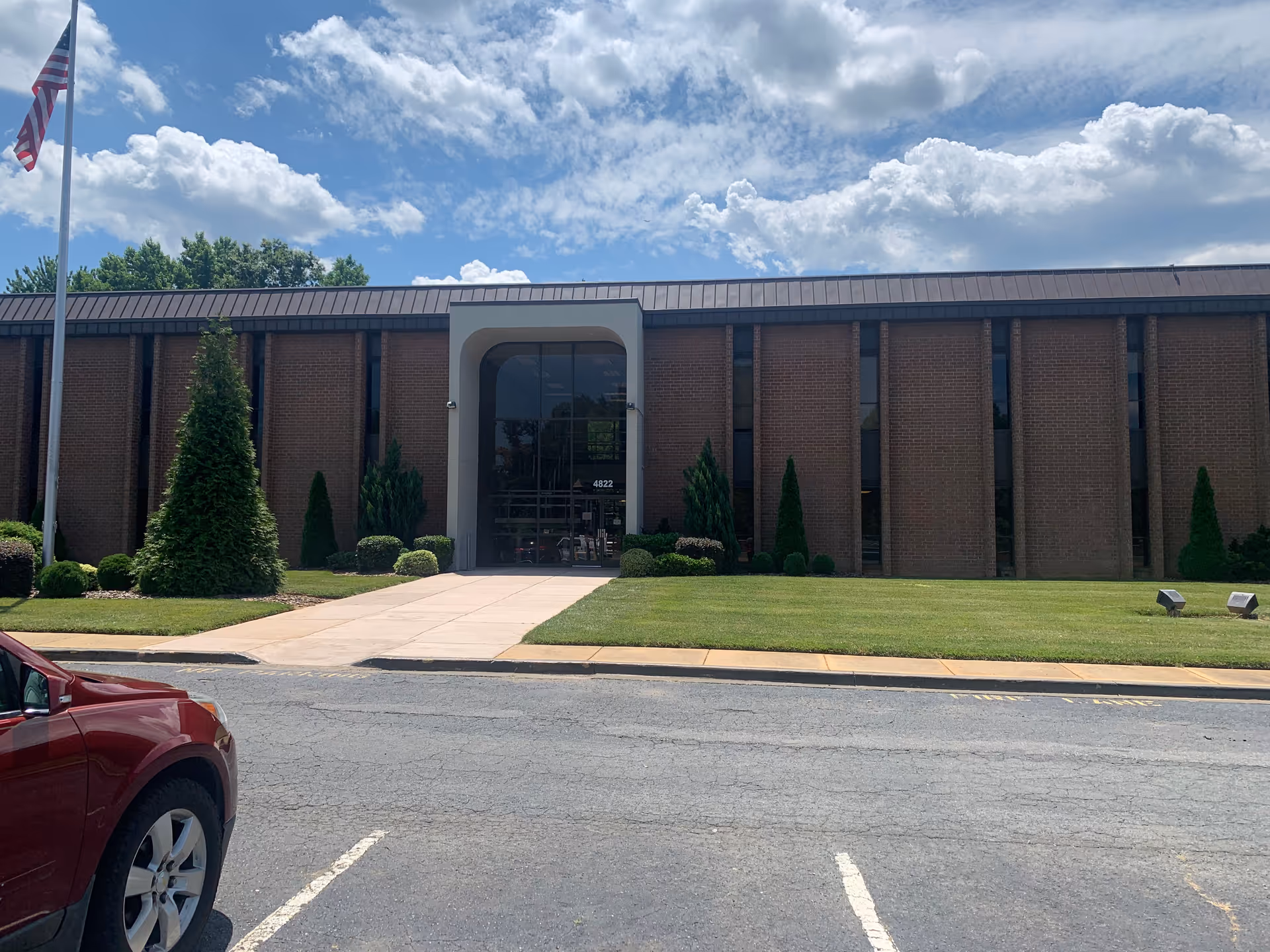 Exterior view of a brick senior living facility with glass entrance and manicured landscaping.
