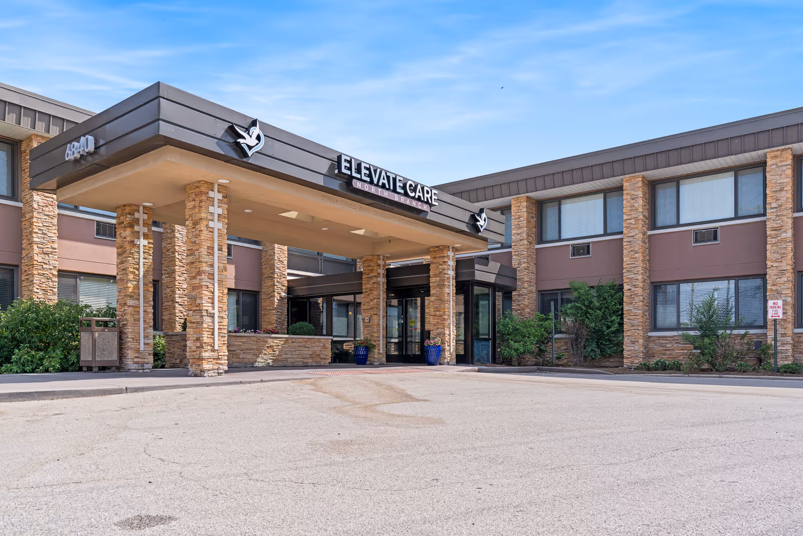 Exterior view of Elevate Care North Branch entrance with stone pillars and glass doors.