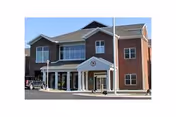 Two-story brick and siding senior living center with glass entrance and curved driveway.