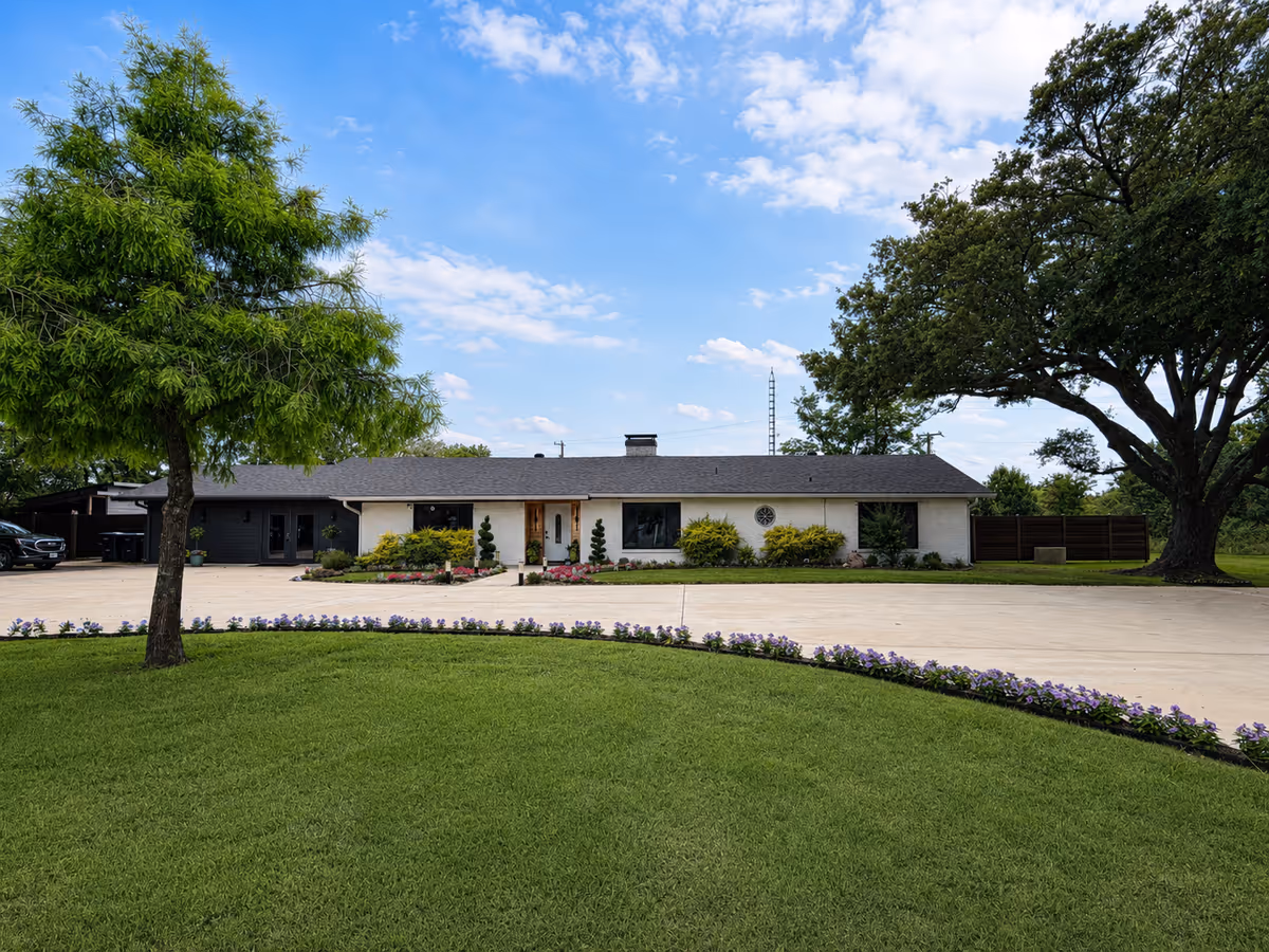 A single-story facility building with manicured lawn, trees, and a wide driveway in front.