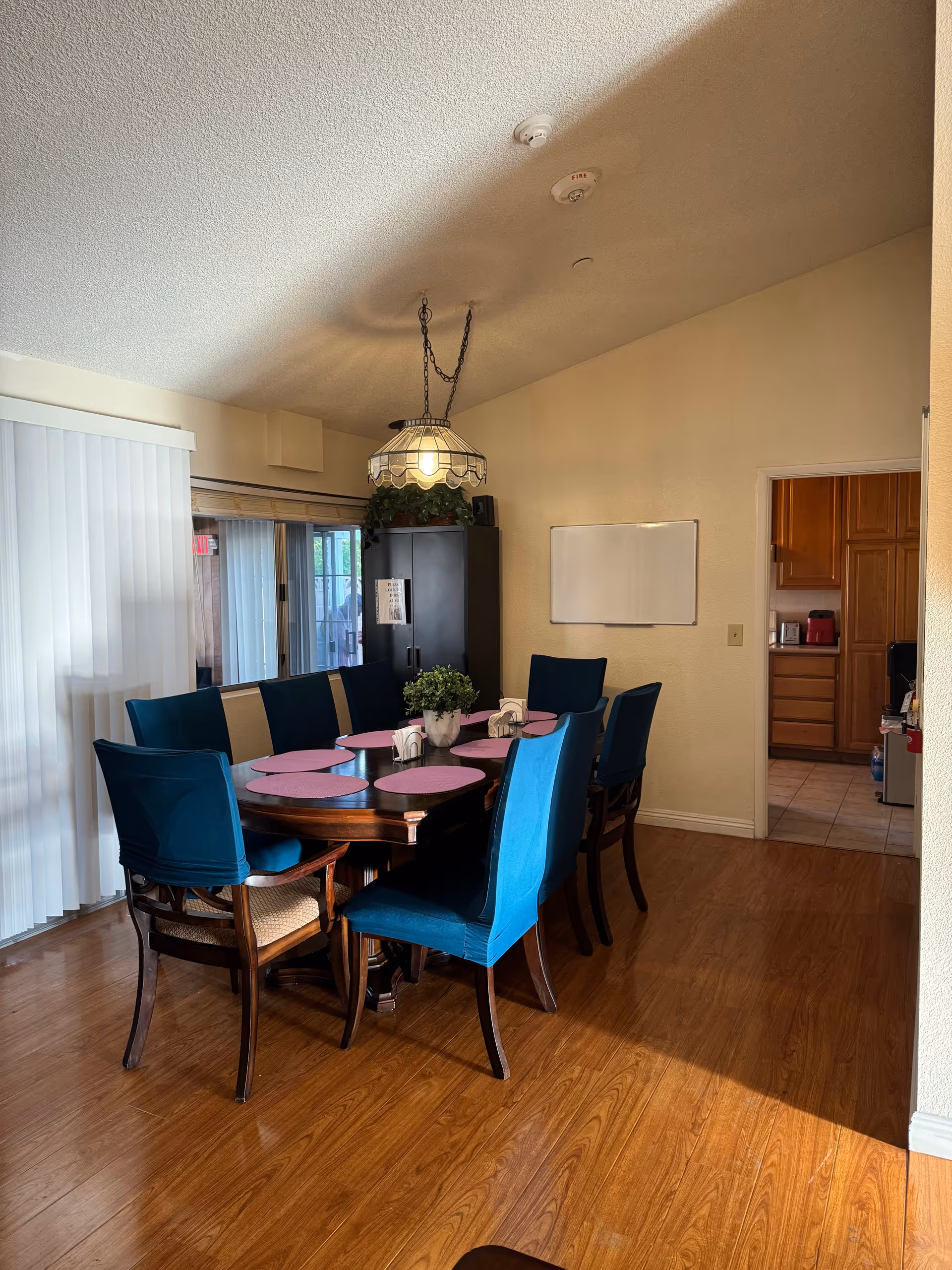 Dining room with blue chairs around a wooden table and pink placemats.