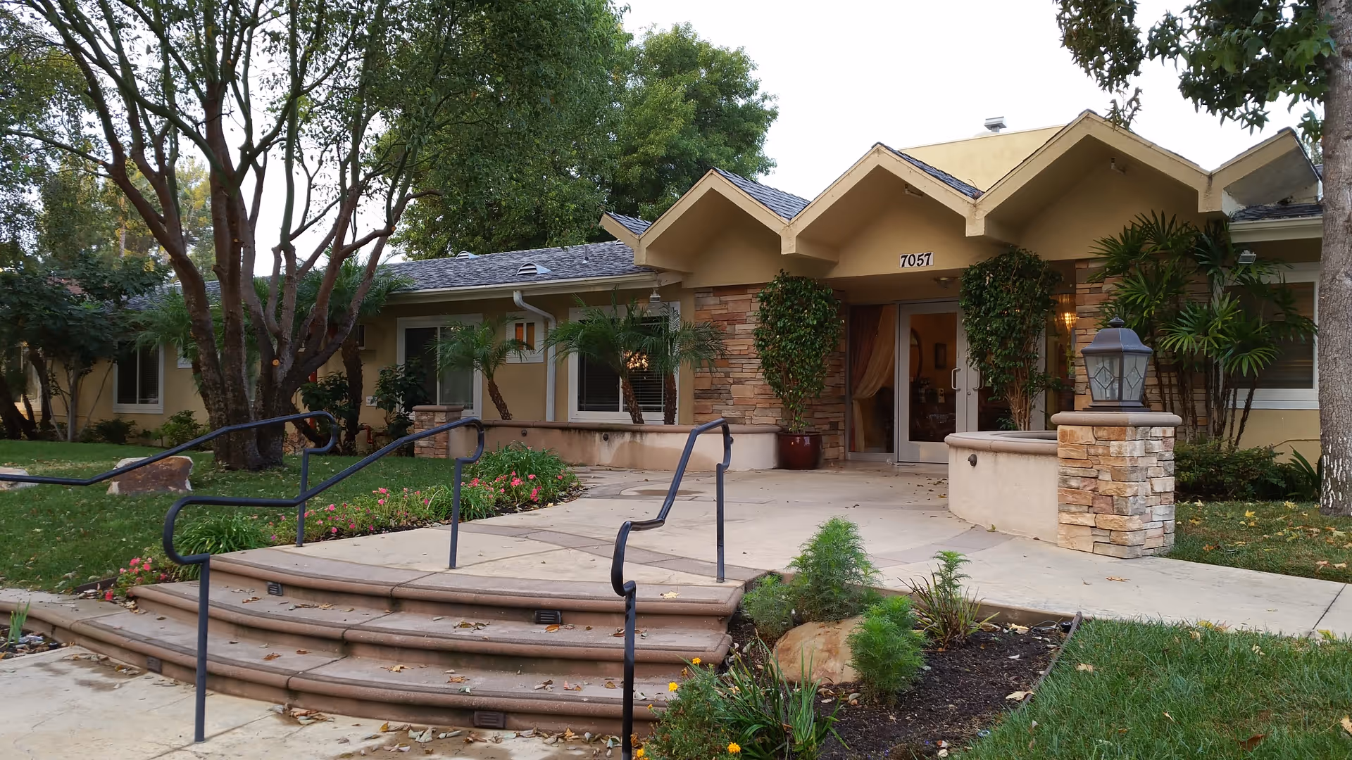 Front entrance of a single-story senior living facility with steps and landscaping.