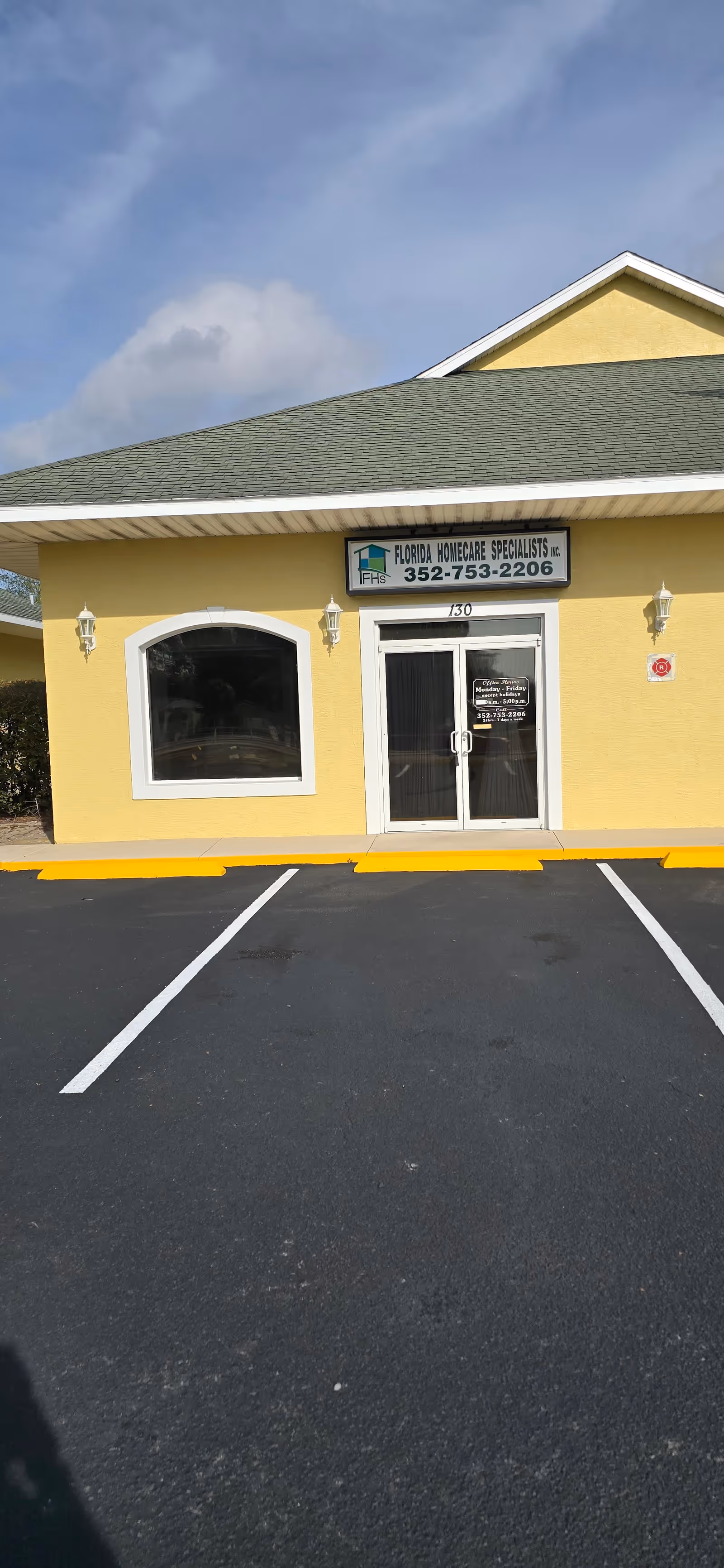 Yellow building entrance with sign Florida Home Care Specialists and a parking lot