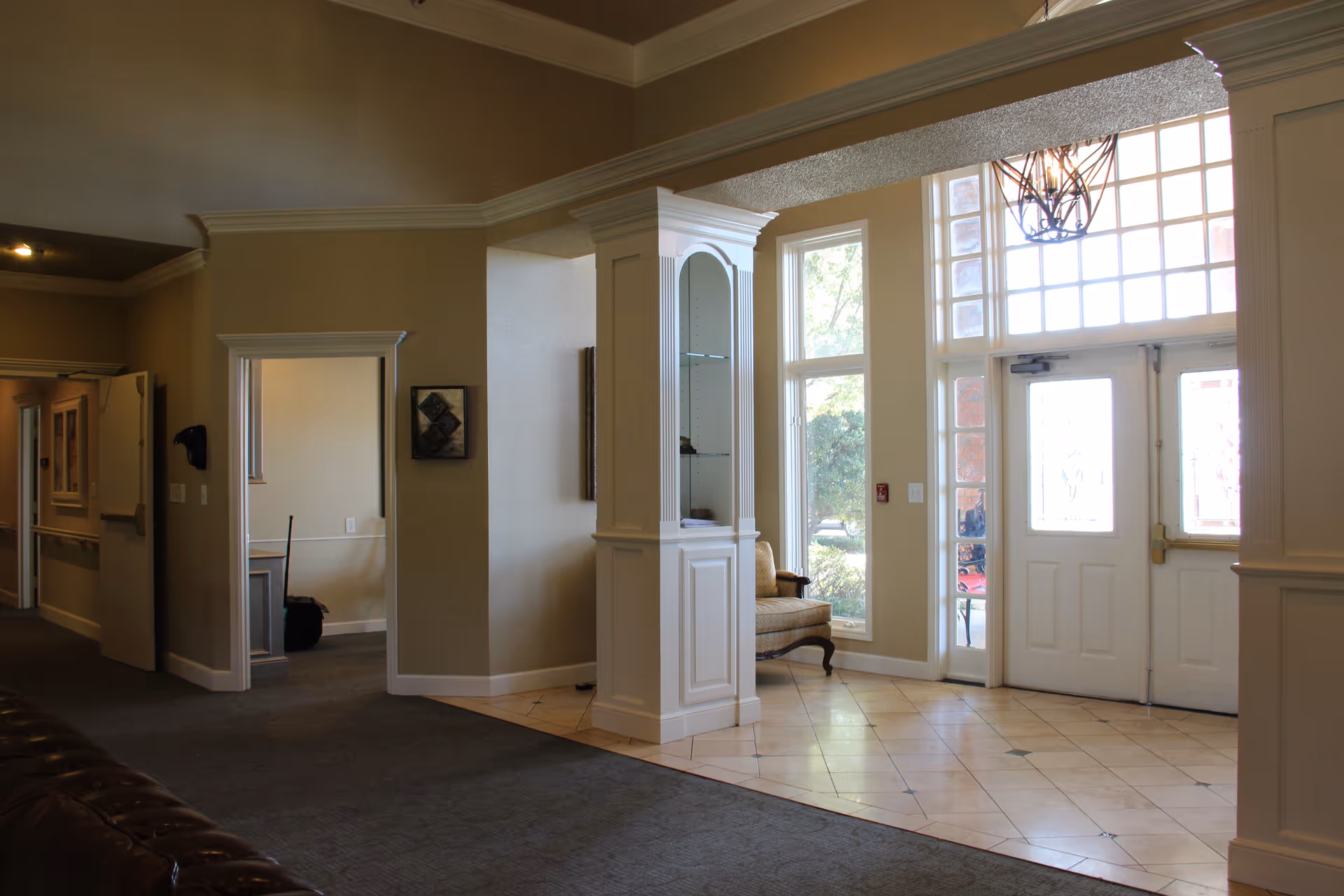 Bright lobby area with tiled flooring, windows, and a seating nook near glass doors.