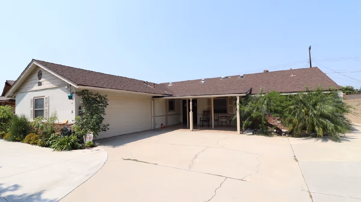 Single-story senior living facility exterior featuring a driveway, garage, and covered entrance.