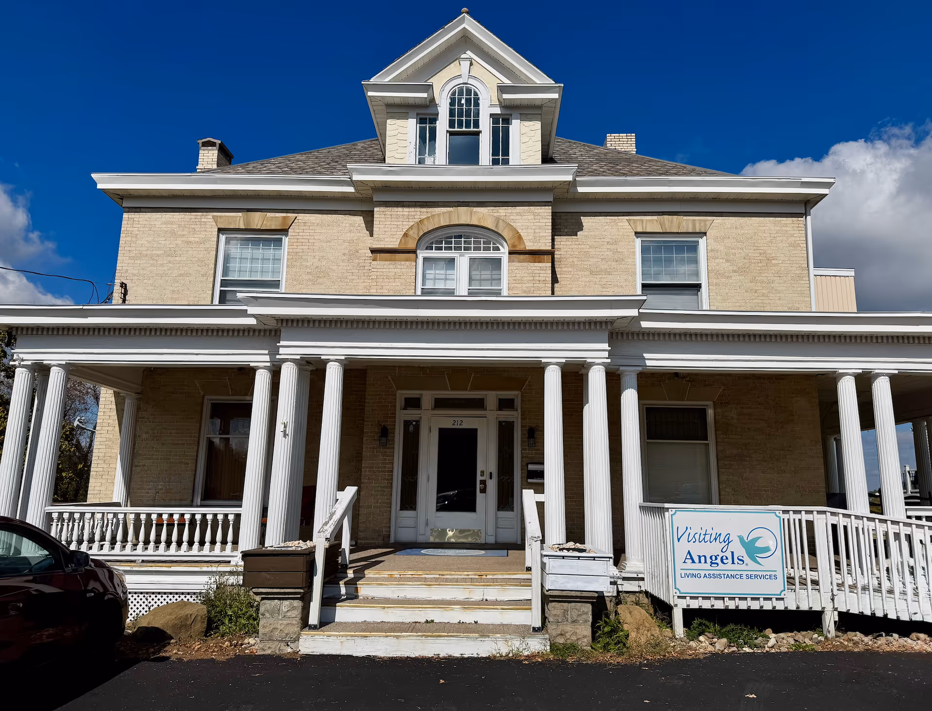 Front view of a brick senior living building with columns and a sign.
