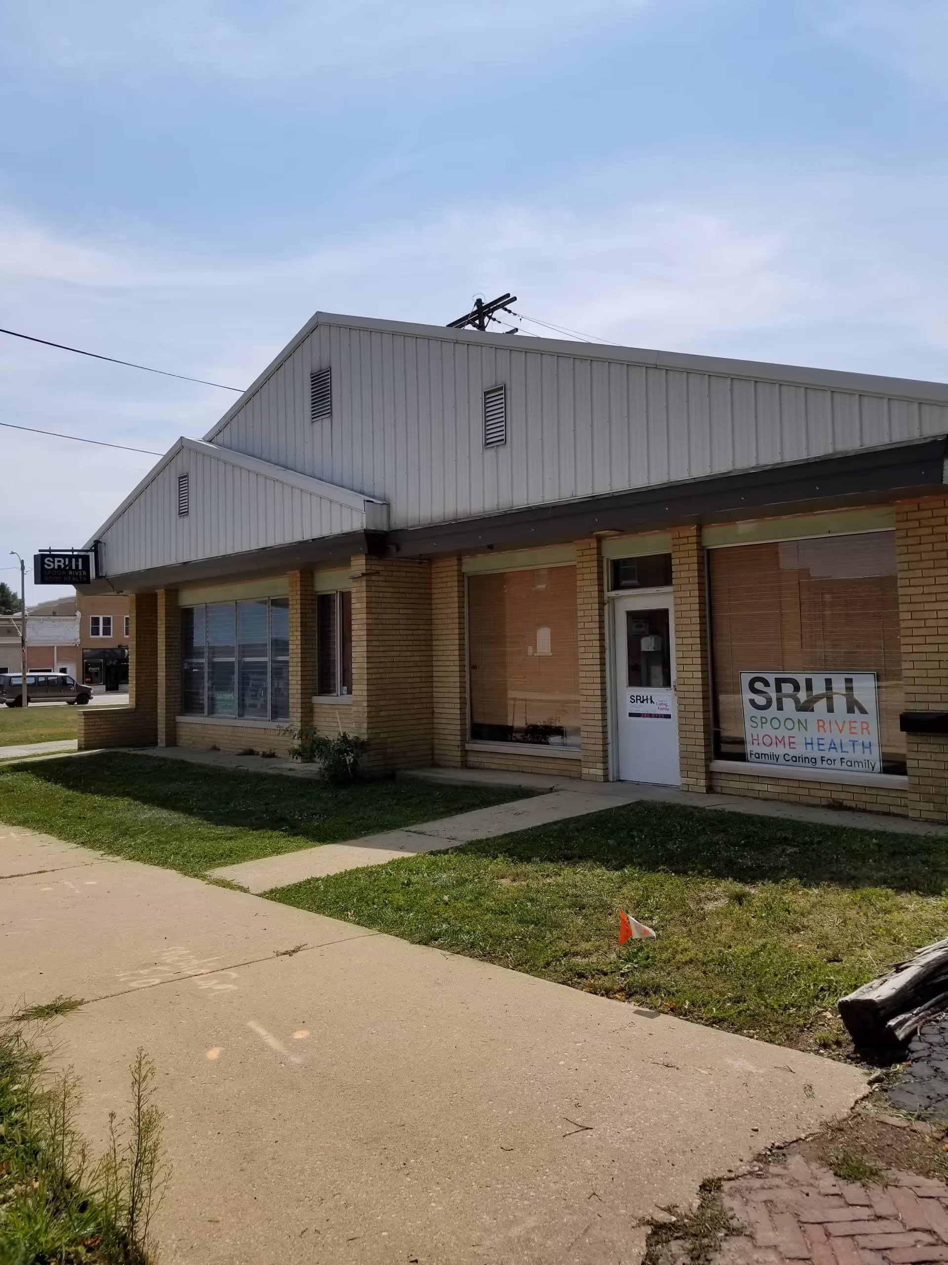 Exterior of Spoon River Home Health Services building with sidewalk and grassy lawn.