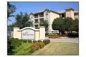 Exterior view of a senior living campus with a front entrance sign and manicured landscaping.