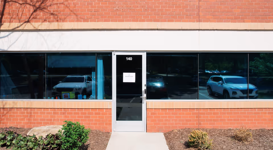 Brick storefront with a central glass door labeled 140, flanked by large windows.