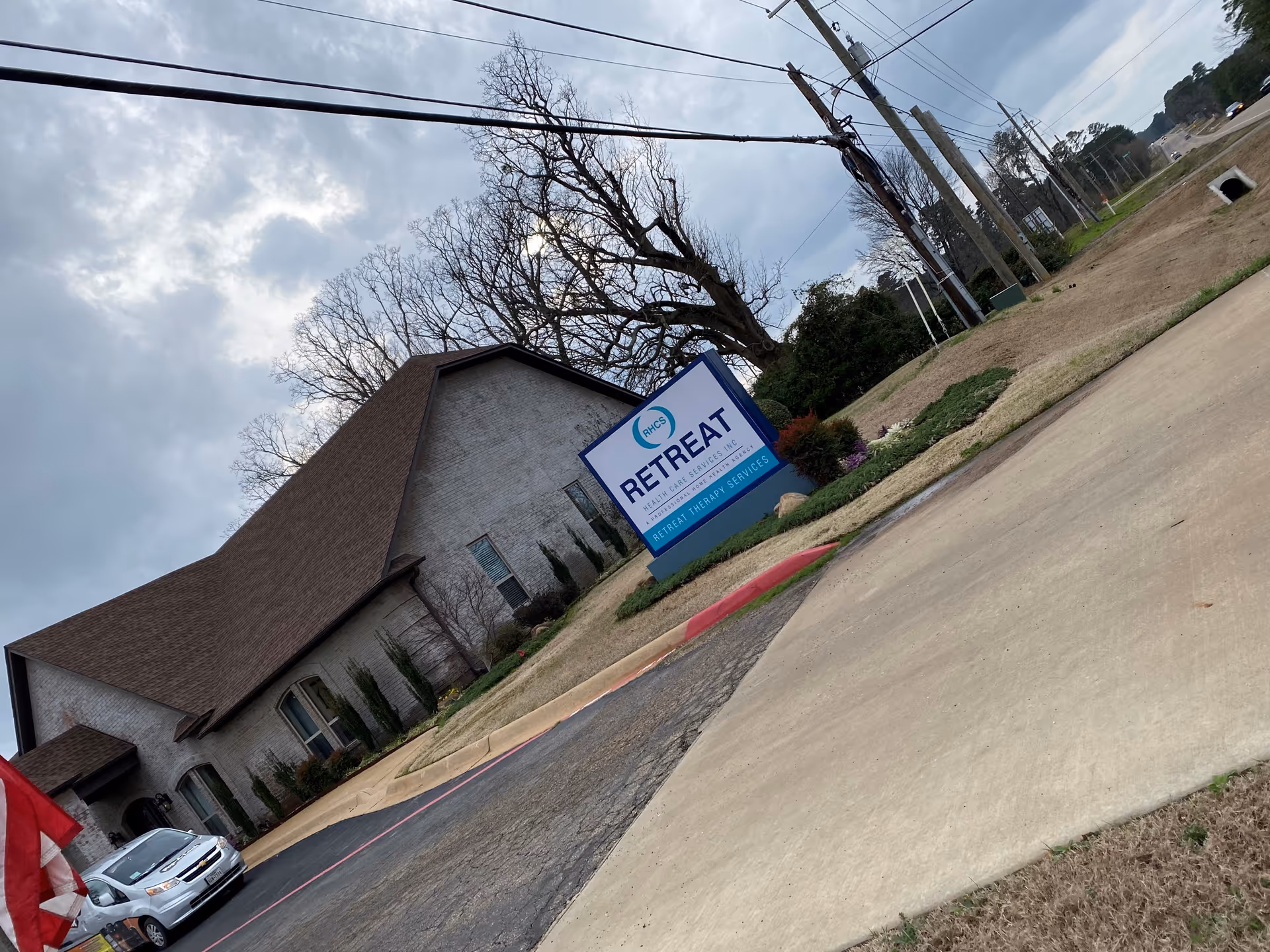Exterior view of a brick facility with a large Retreat sign by the parking.