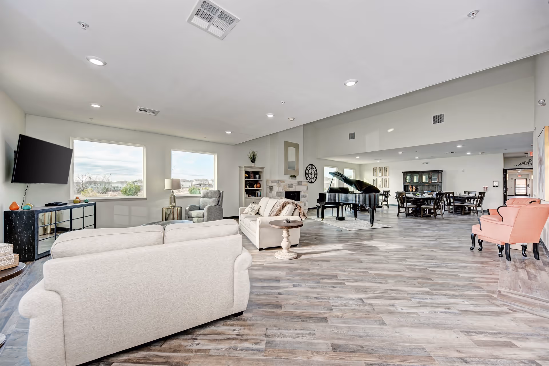 Spacious, bright common living area with sofas, armchairs, a grand piano and dining tables.