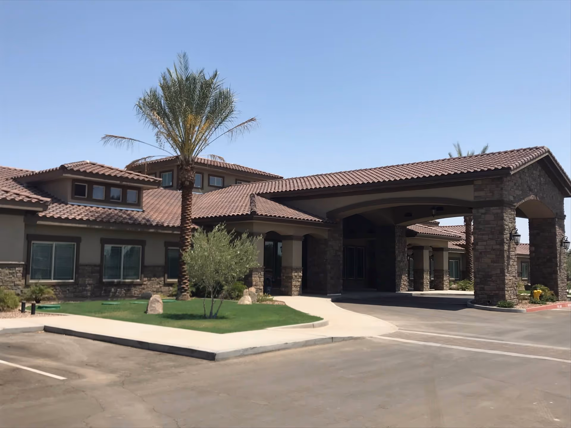 Exterior of Parkland Memory Care with stone facade, porte-cochere, and palm trees