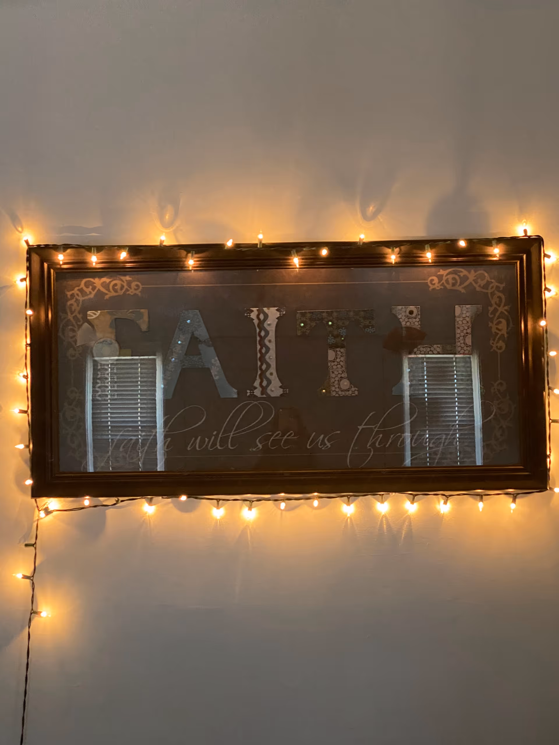 Framed wall art with string lights decorates an indoor wall in soft warm glow.