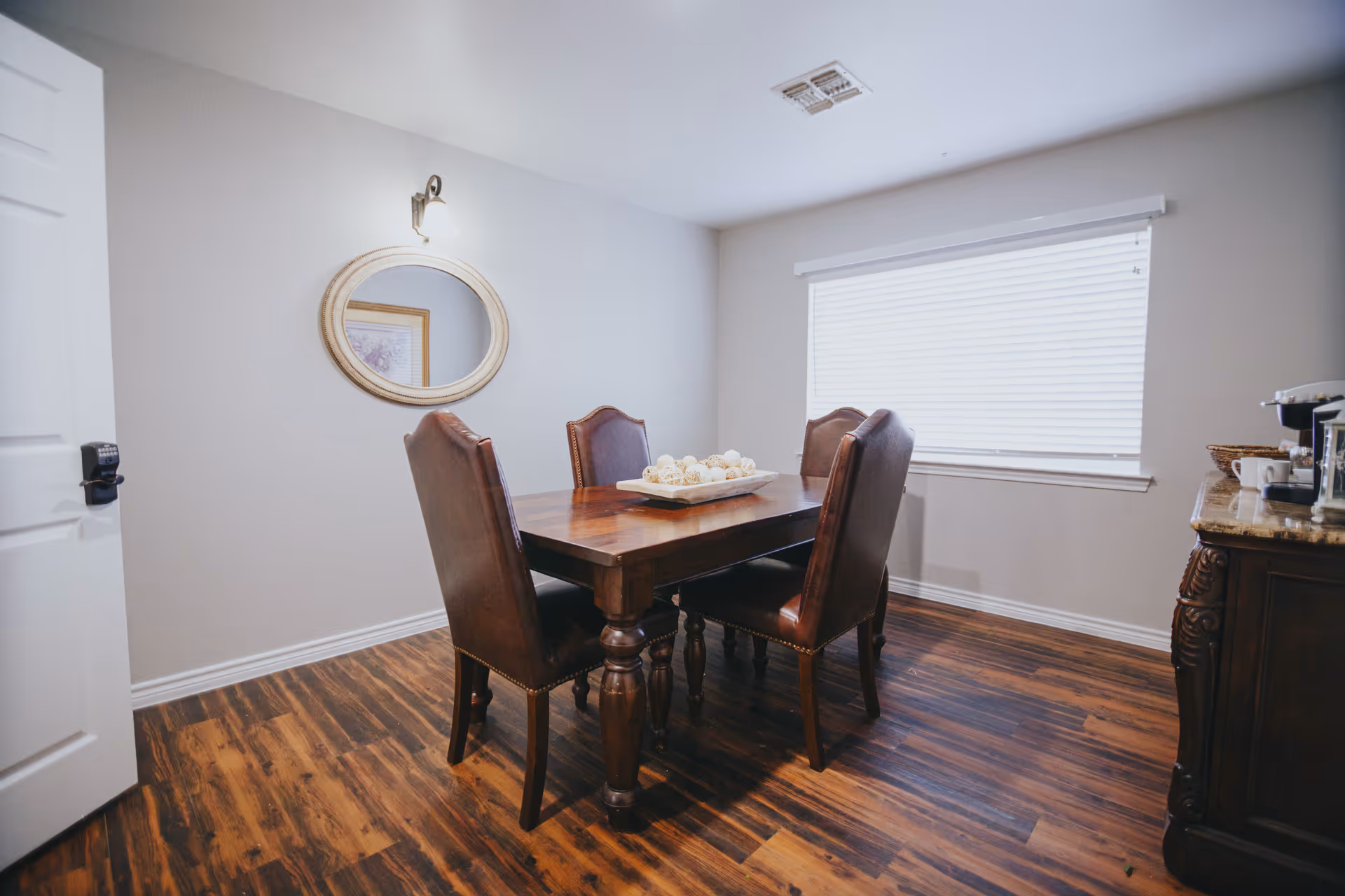 Dining room with a wooden table, four upholstered chairs, and window blinds.