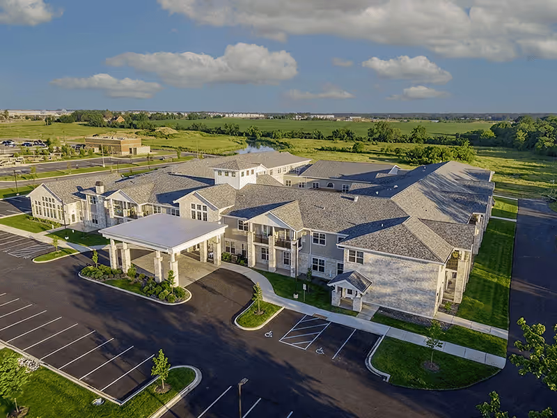 Large, modern senior living facility exterior with a covered entrance and ample parking.