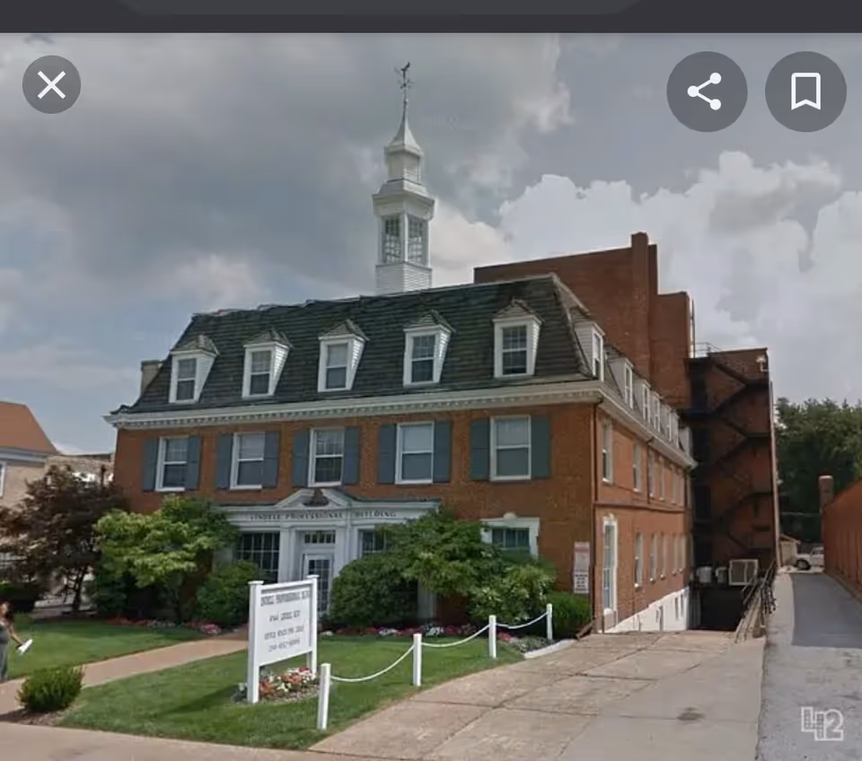 Exterior view of a brick senior living building with dormers and a cupola.