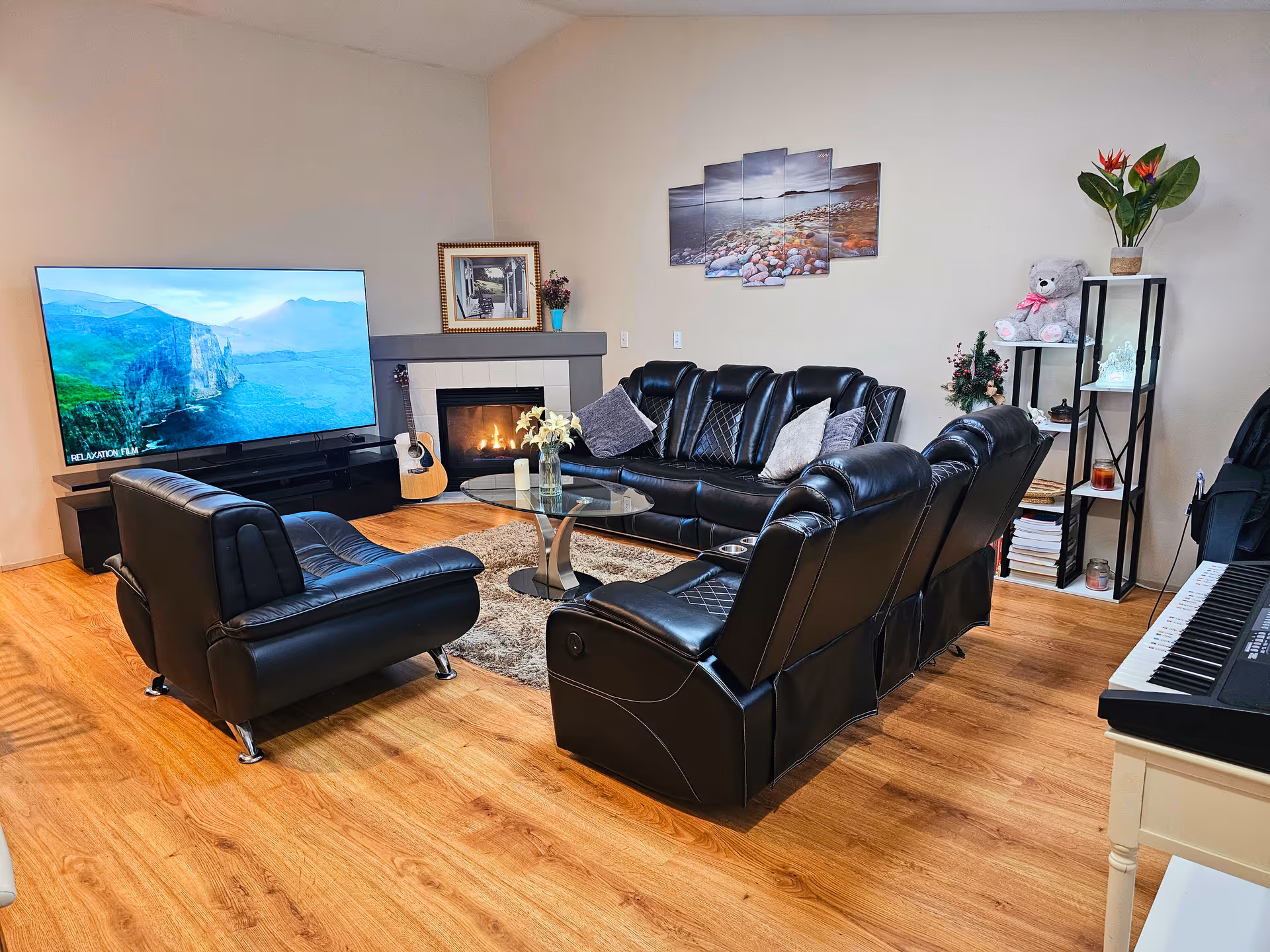 Living room with black leather sofas, coffee table, fireplace, and wall art.