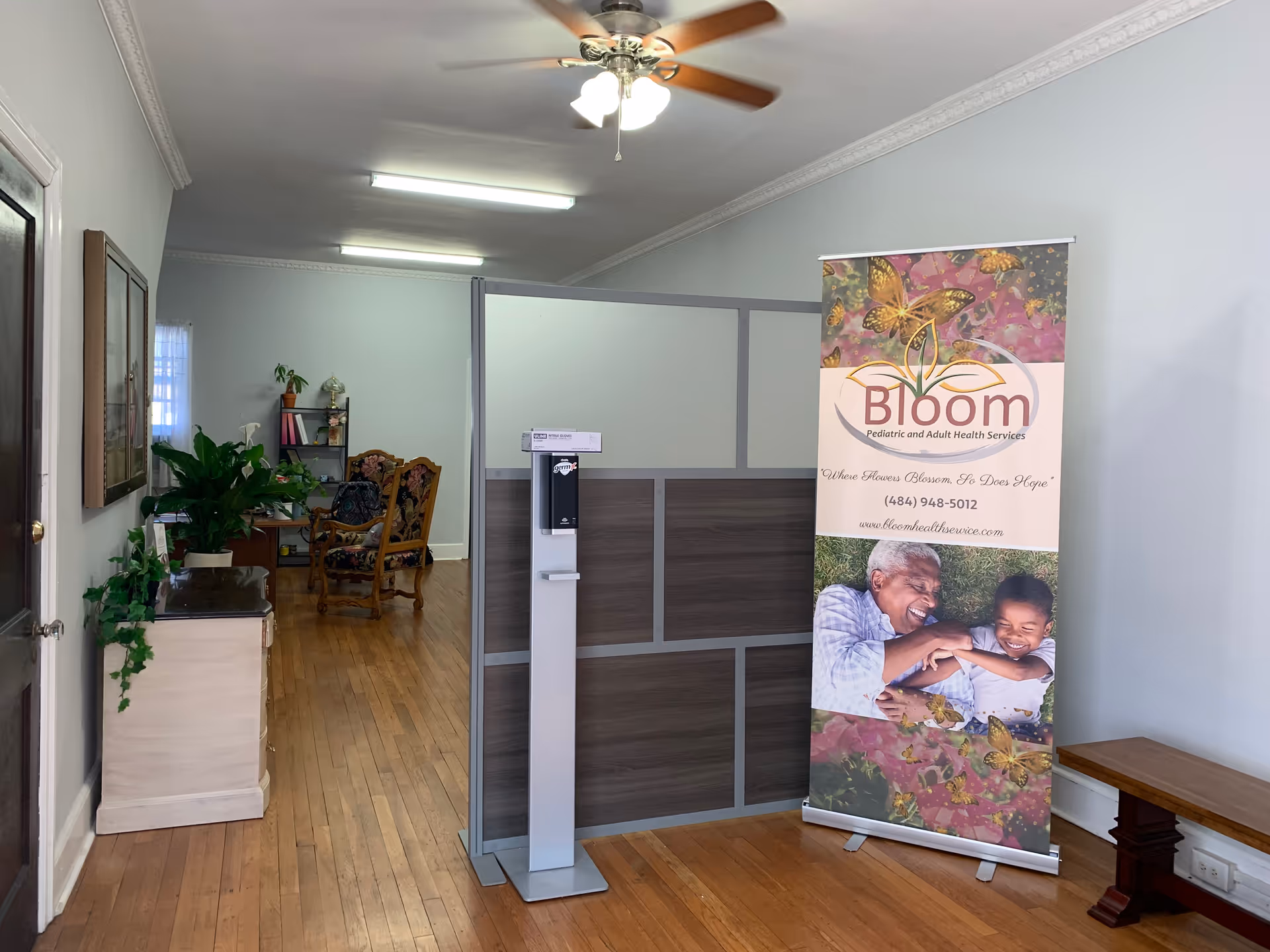 Reception area with banner, partition, plants, and seating inside Bloom Pediatric and Adult Health Services.