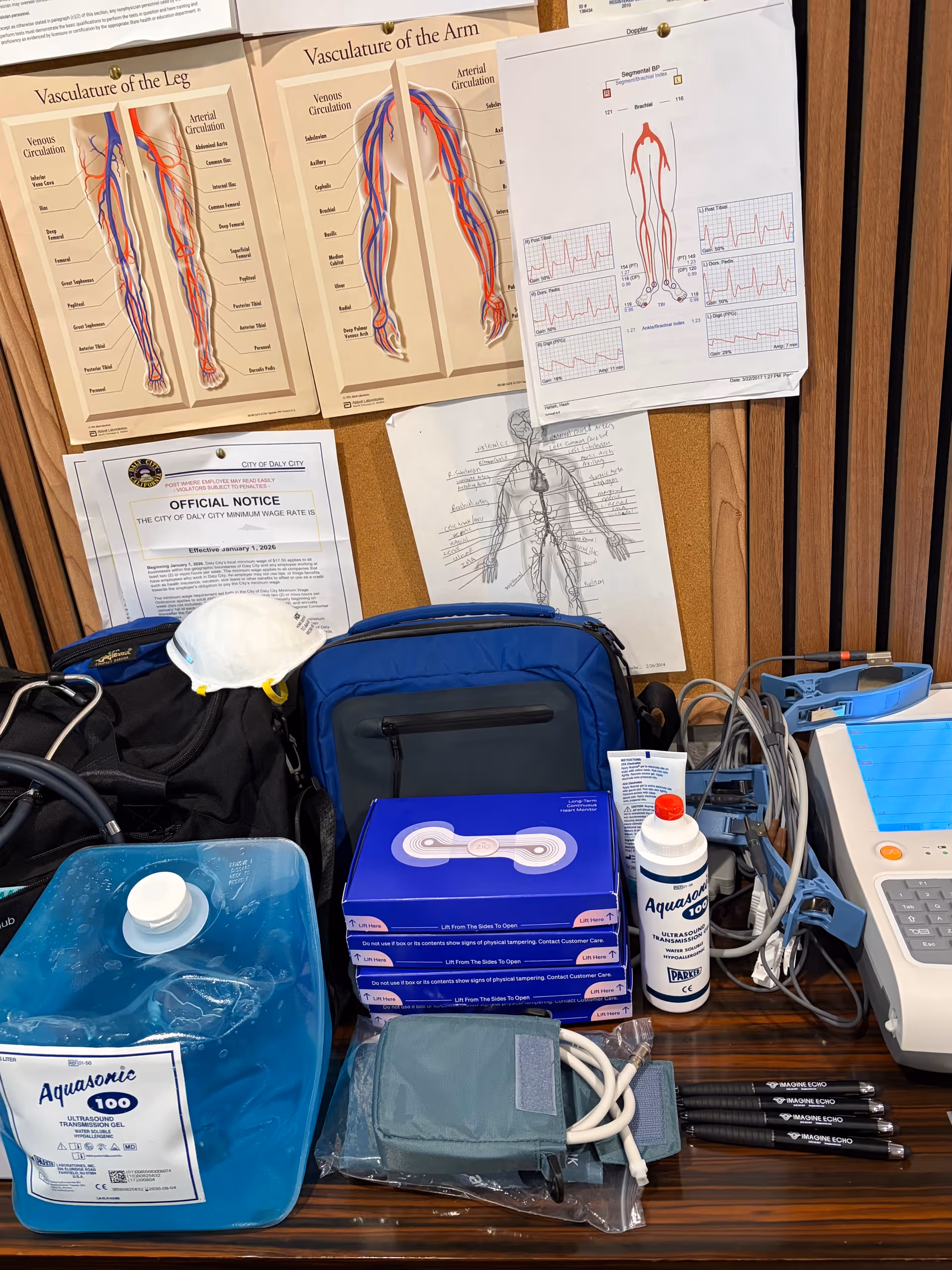 Medical posters, supplies, and equipment spread across a cluttered clinical workstation.
