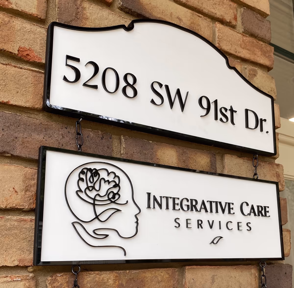 Exterior brick wall with two hanging signs; address and Integrative Care Services logo.