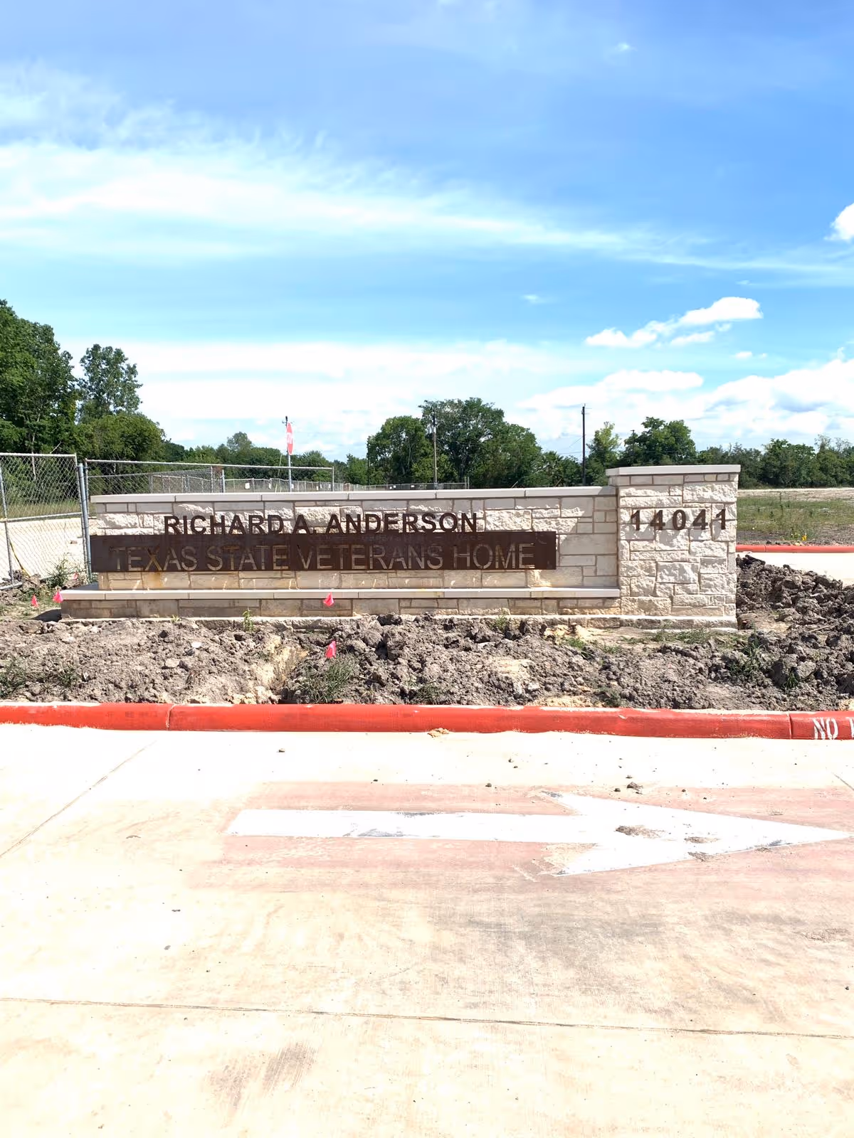 Stone entrance sign reads Richard A. Anderson Texas State Veterans Home with dirt landscaping.