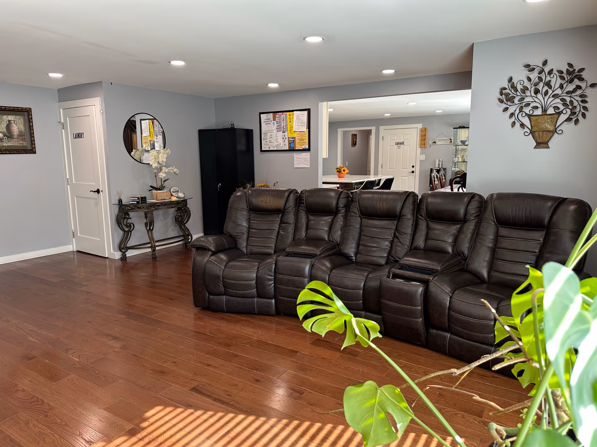 Spacious living room with brown leather recliners, hardwood floors, and decorative plants.