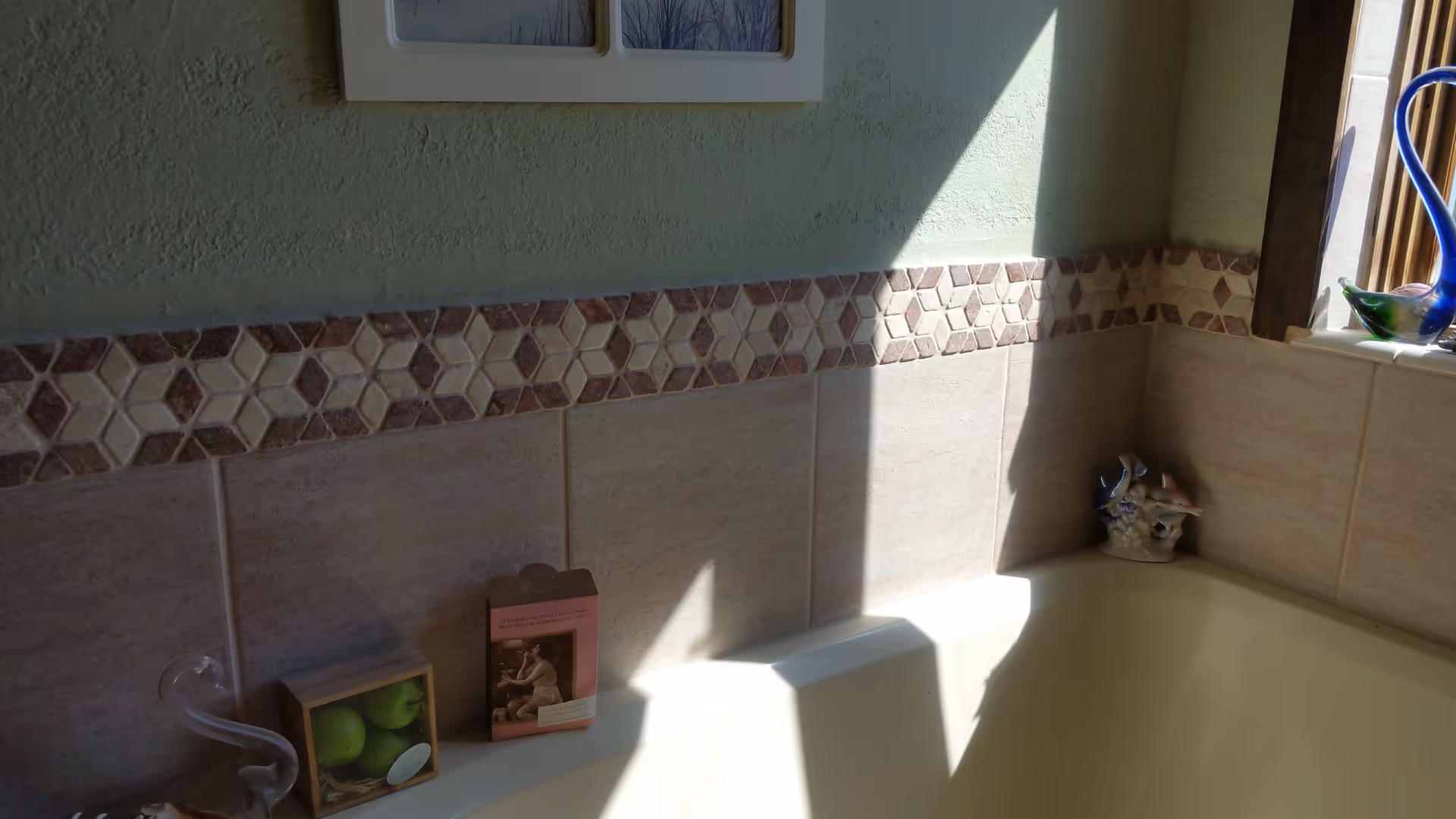 Bathroom interior with beige tiles, a bathtub, window, and decorative items