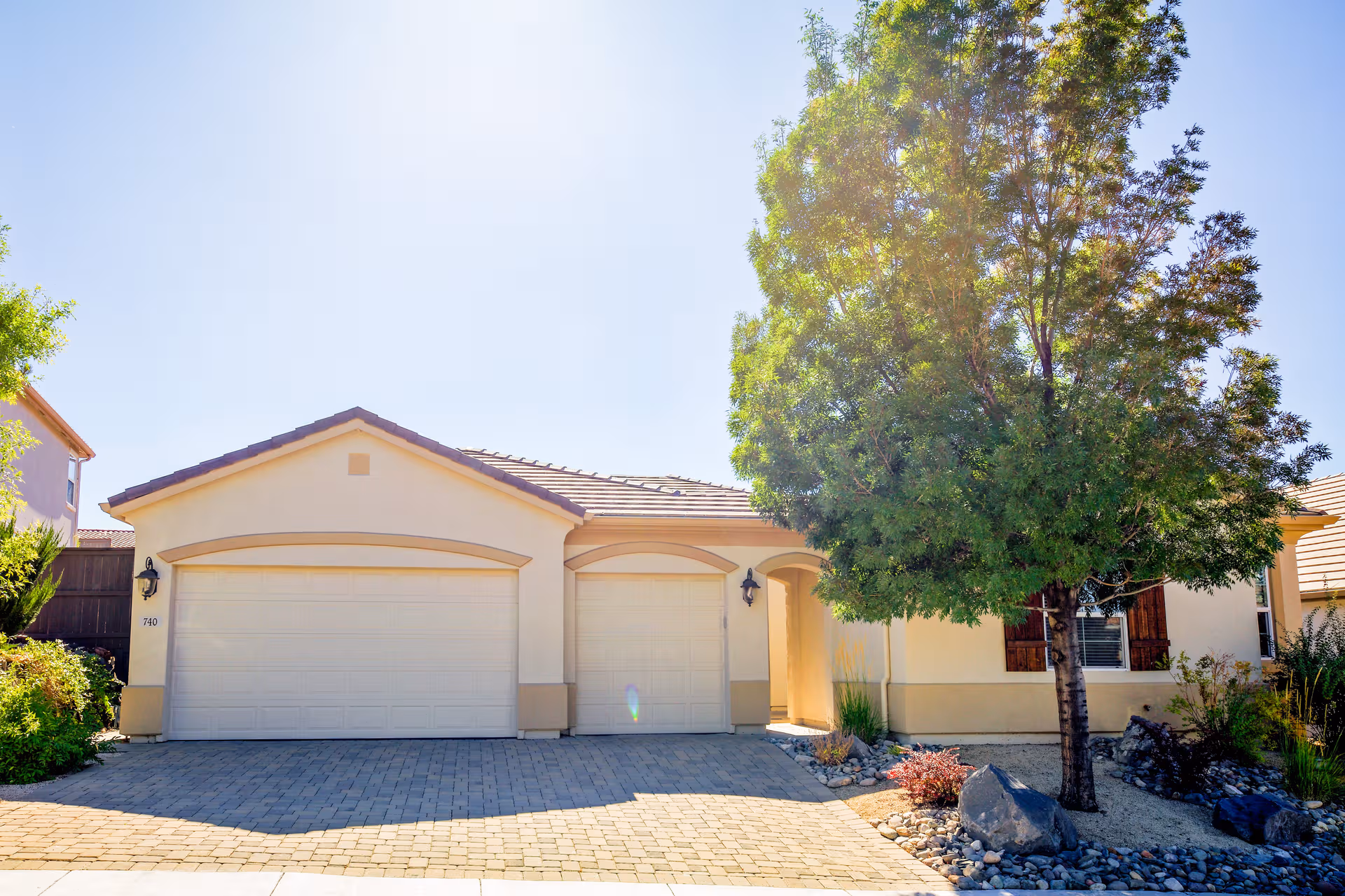 Front exterior of Corinthian Place South LLC facility with three garage doors and a tree.