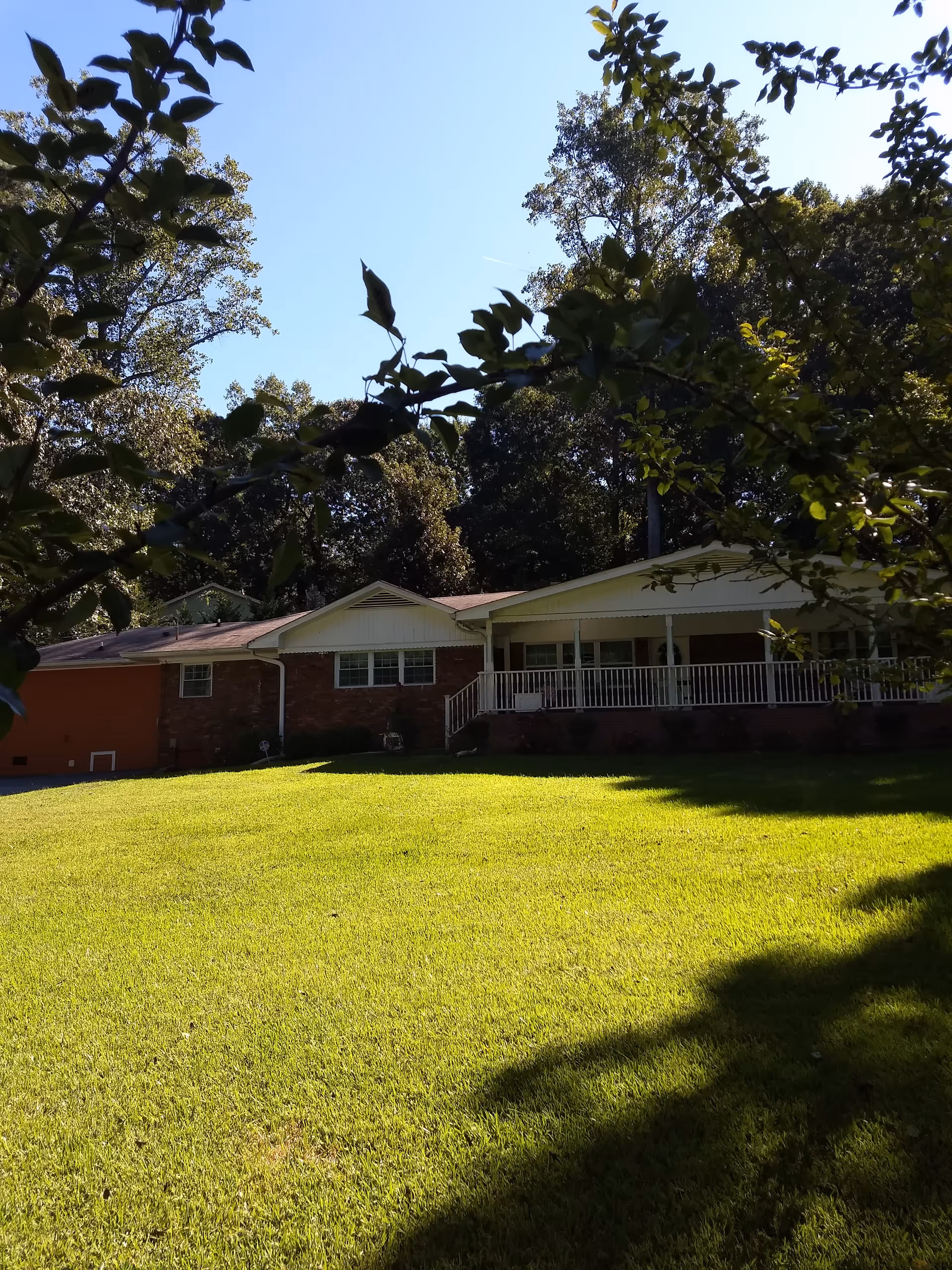 Single-story brick senior living facility with a wide front porch and grassy lawn.