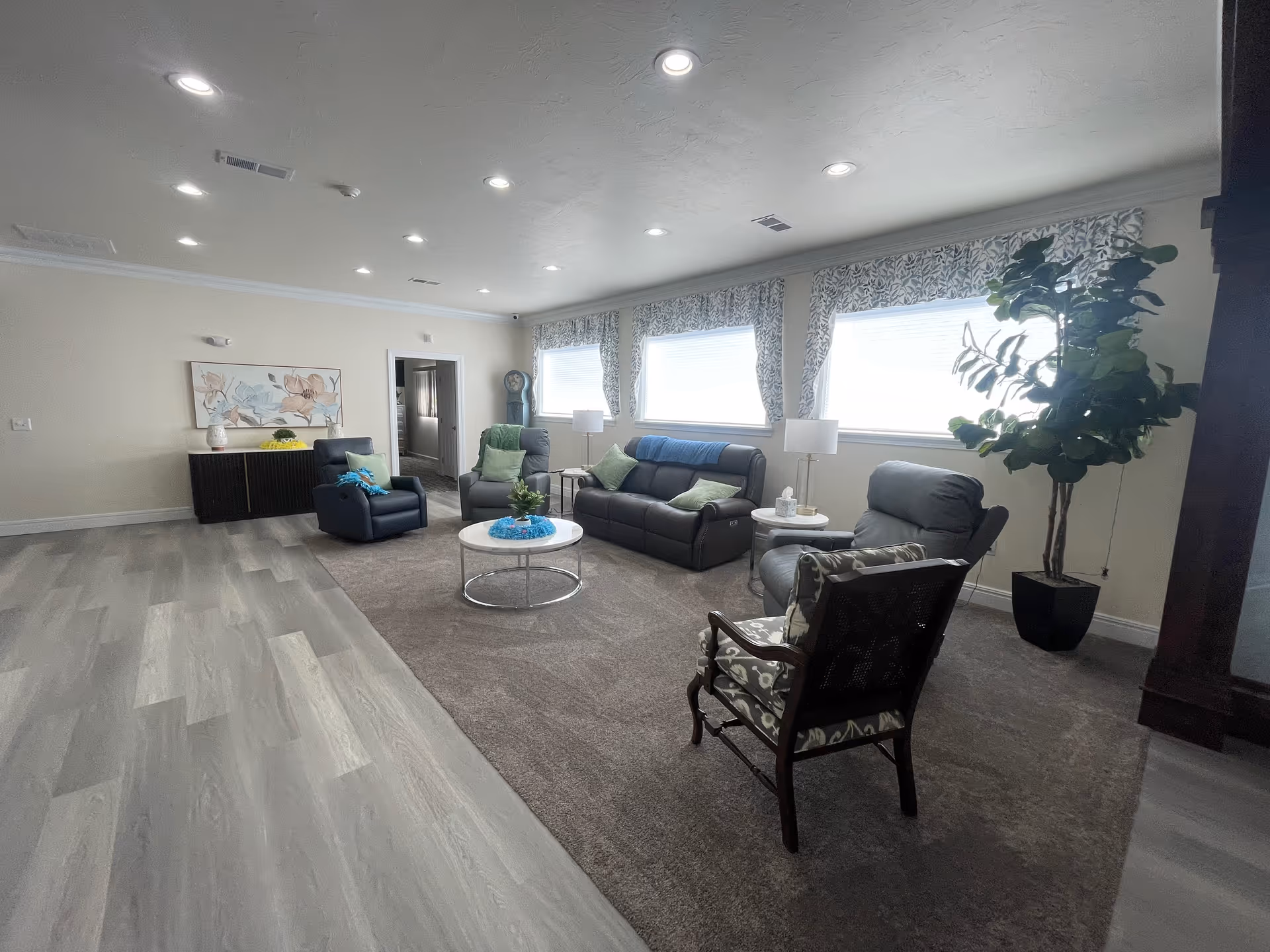 Senior living facility lounge with multiple sofas, chairs, and large windows.