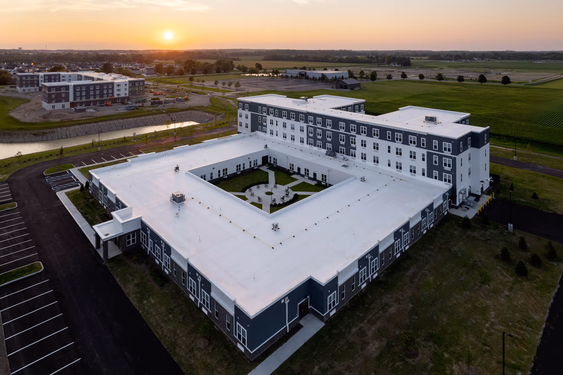 Aerial view of Vita Senior Living of Greenfield complex with white rooftops and surrounding farmland.