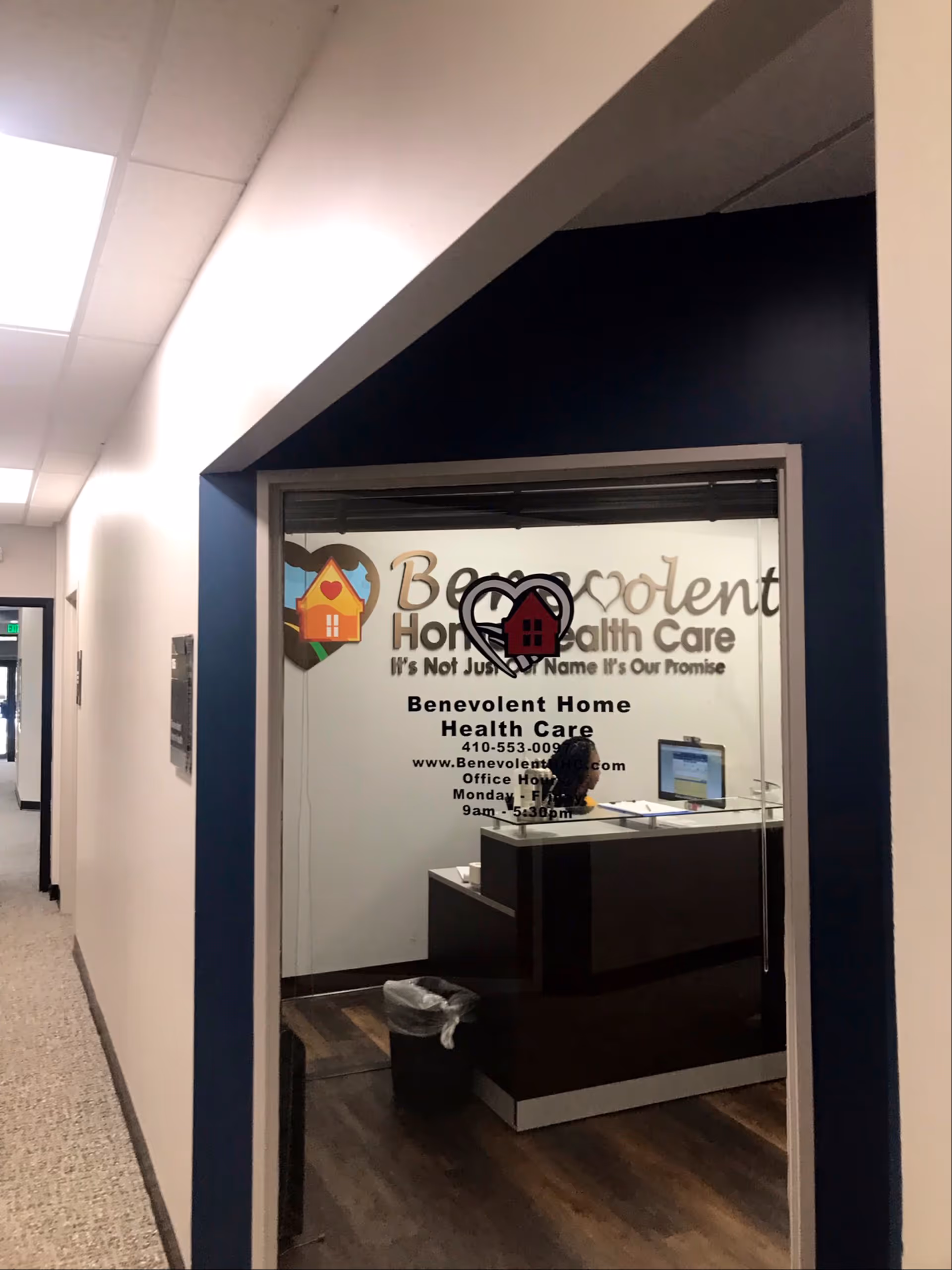Interior hallway with reception desk behind a glass front displaying Benevolent Home Health Care sign.