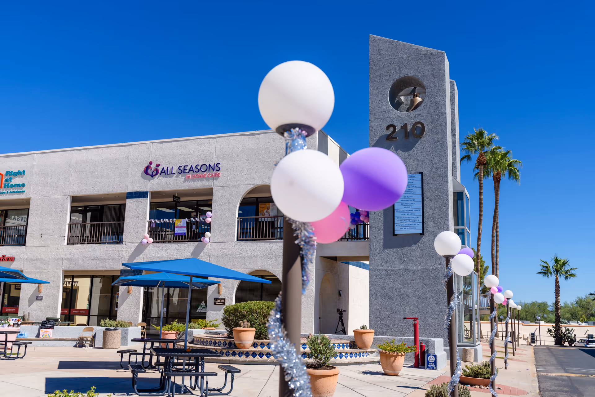 Exterior view of All Seasons In Home Care LLC building with balloons and blue sky.