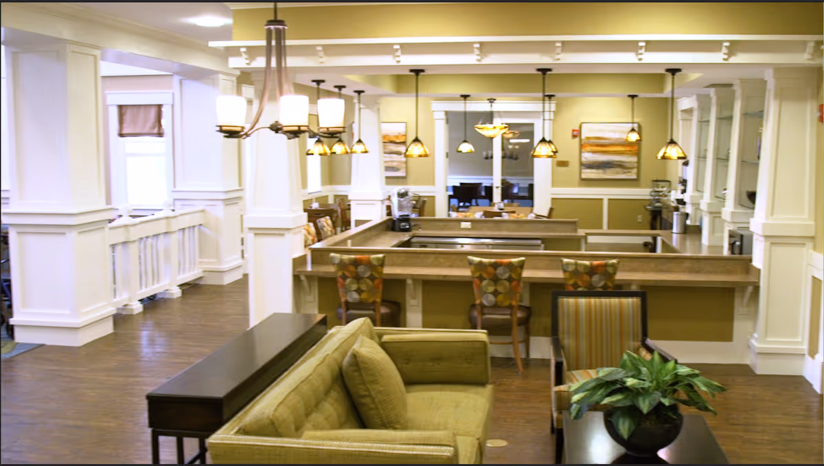 Spacious interior lounge with a long central counter, stools, couches, and warm lighting.