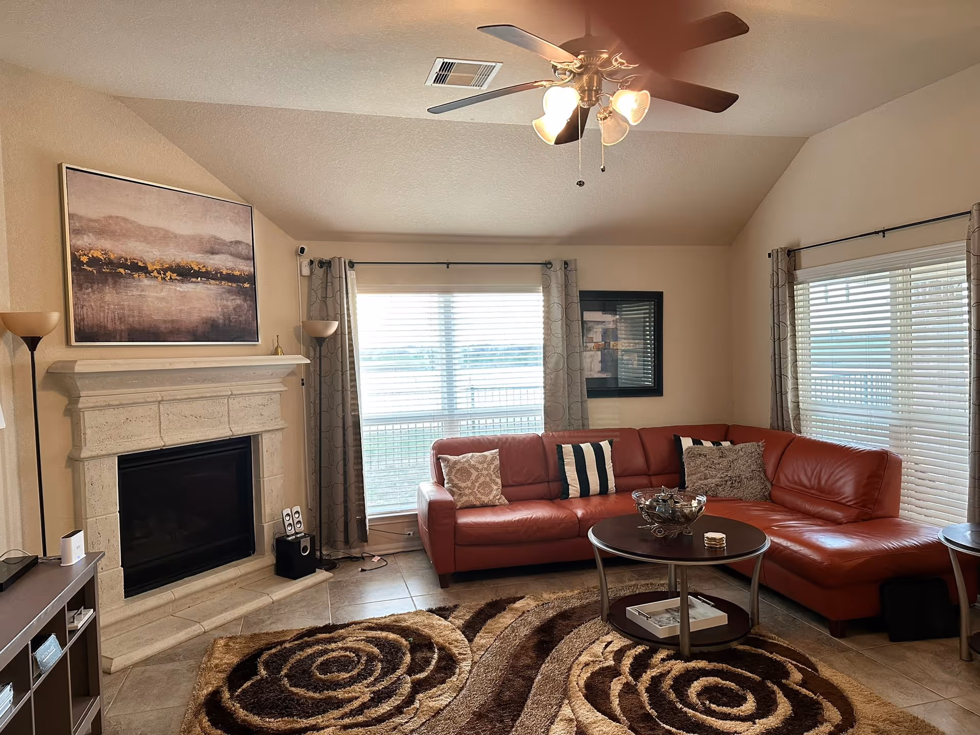 Bright living room with red sectional sofa, fireplace, coffee table, and large windows.
