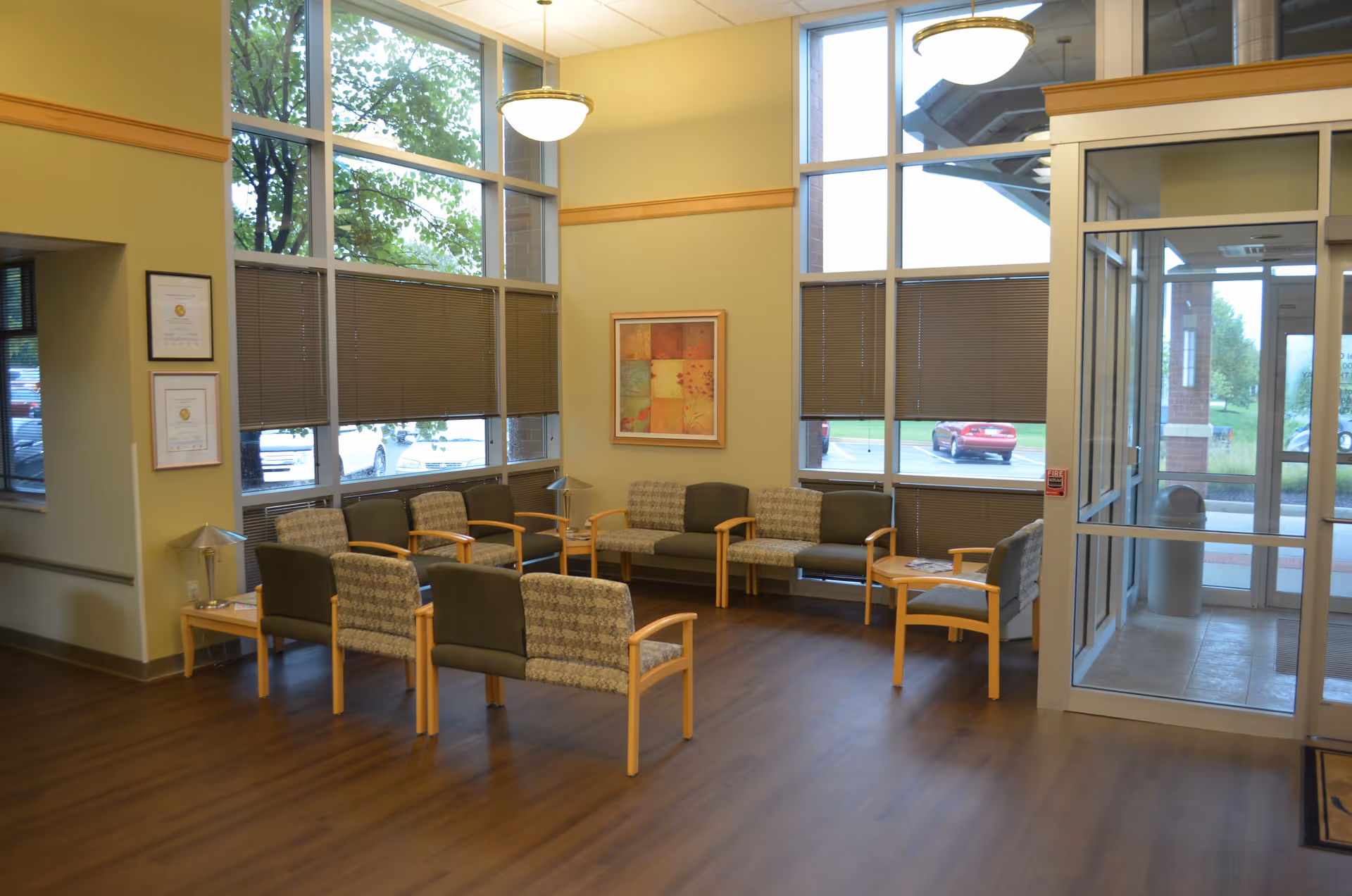 Interior waiting area with arranged chairs and large windows near a glass entrance.