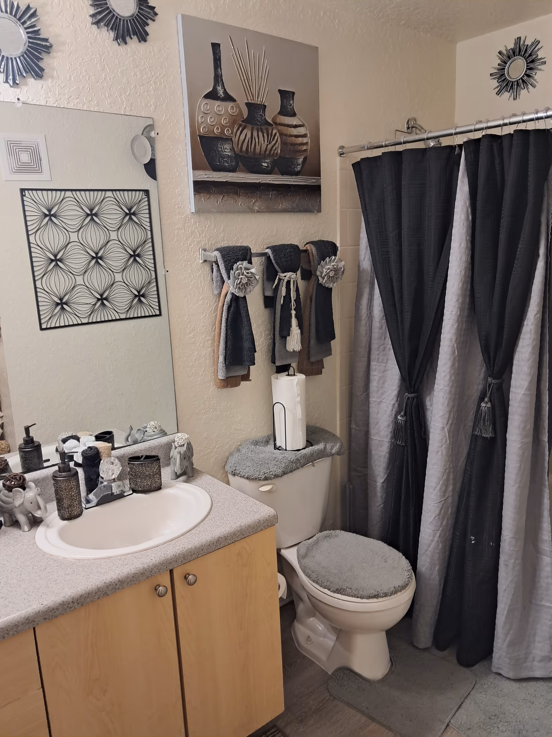 Bathroom with sink, toilet, shower curtain, towels, and wall art in a senior living setting.