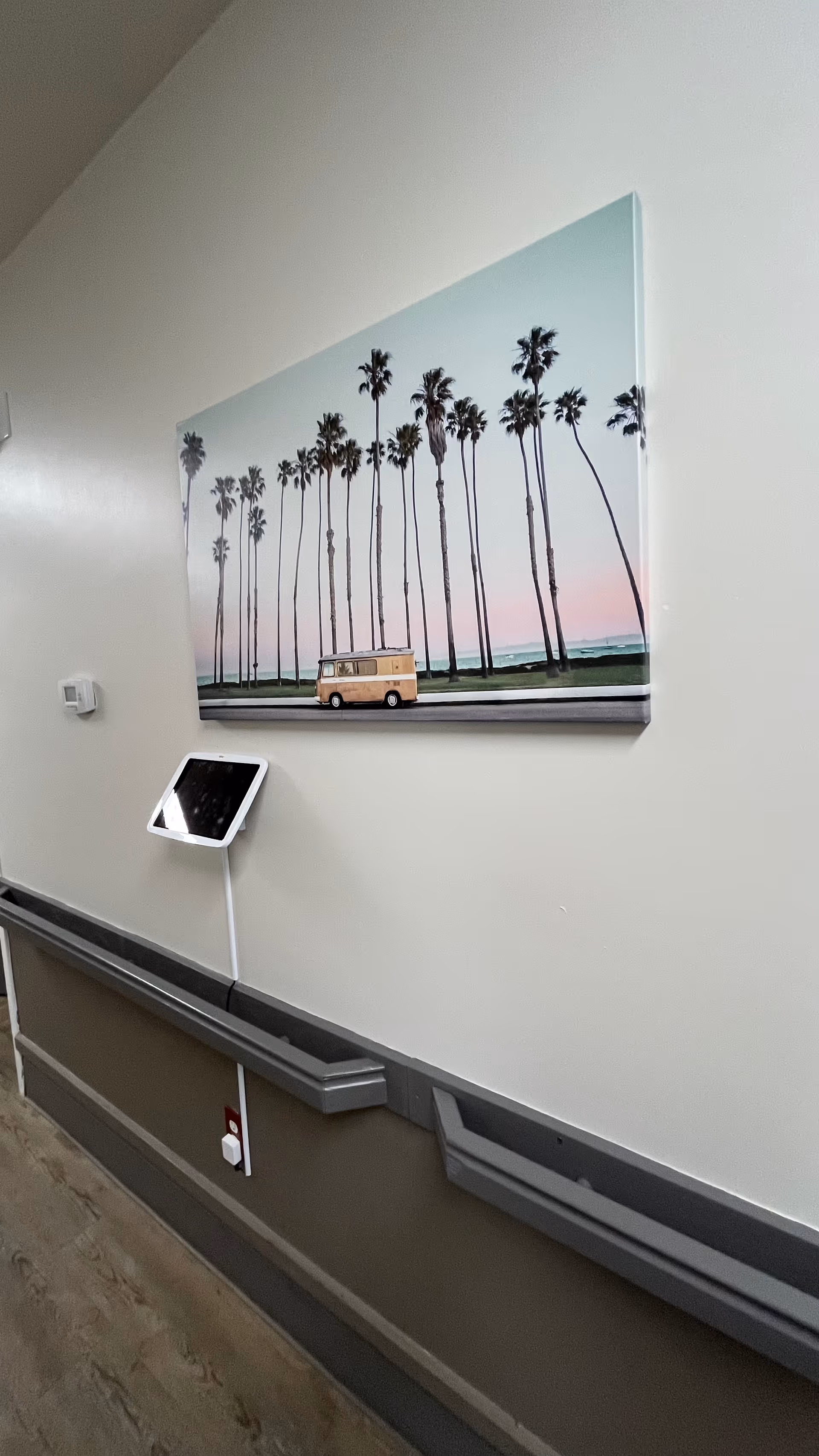 Interior hallway with palm-tree artwork and a wall-mounted tablet.