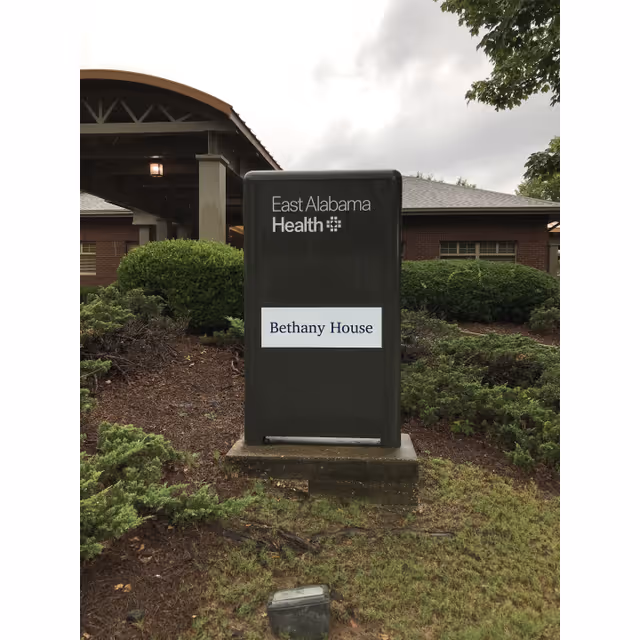 Tall dark exterior sign reading East Alabama Health and Bethany House, placed in landscaped front area.
