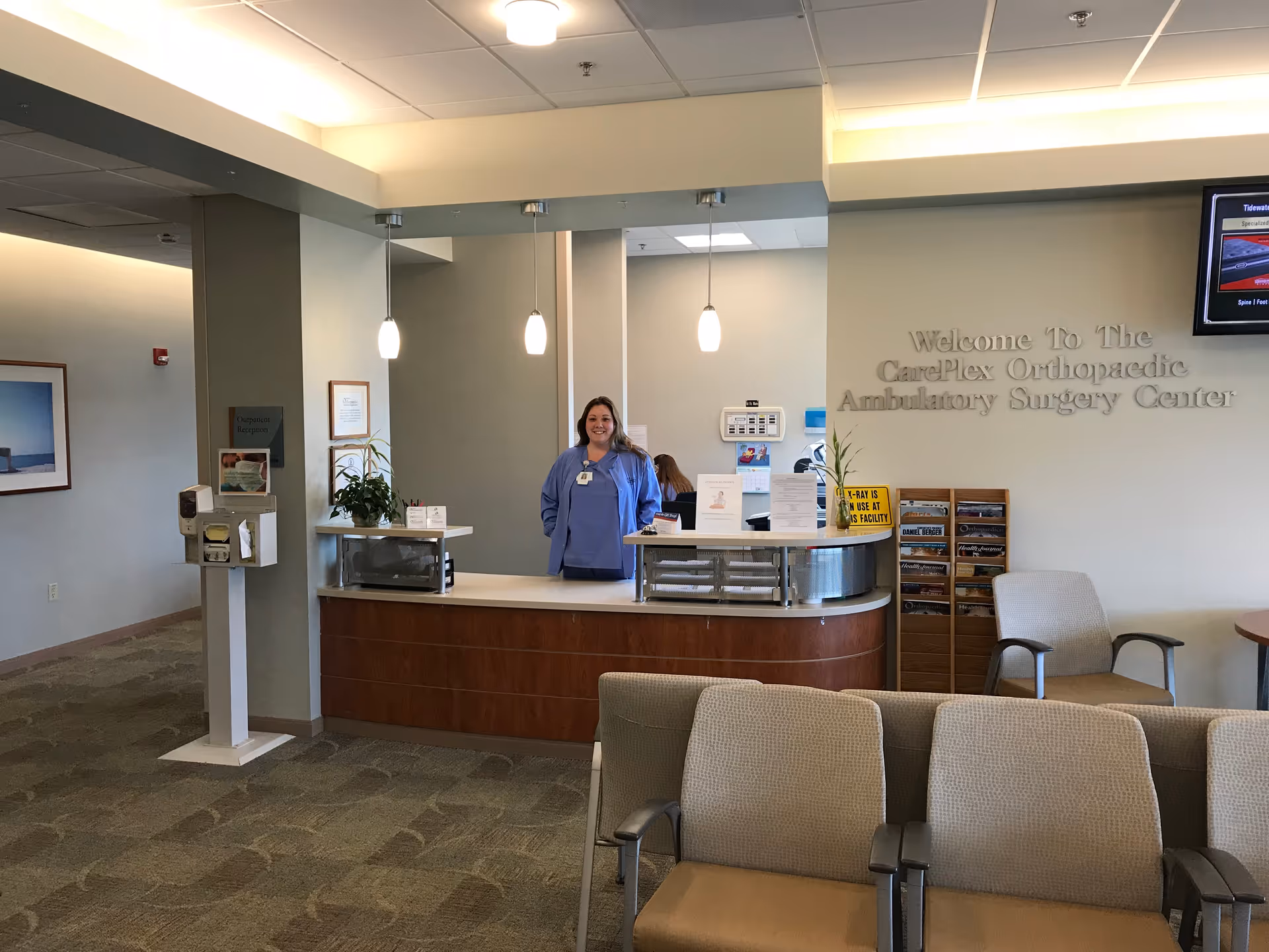 Reception desk with staff in blue scrubs in a medical center lobby.