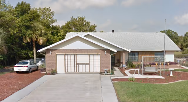 Front exterior of a single-story brick senior living facility with a driveway.