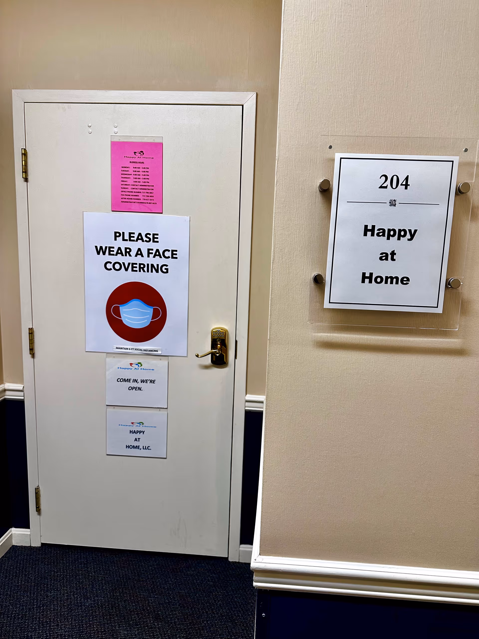 Interior door with posted notices and a wall sign reading Happy at Home 204