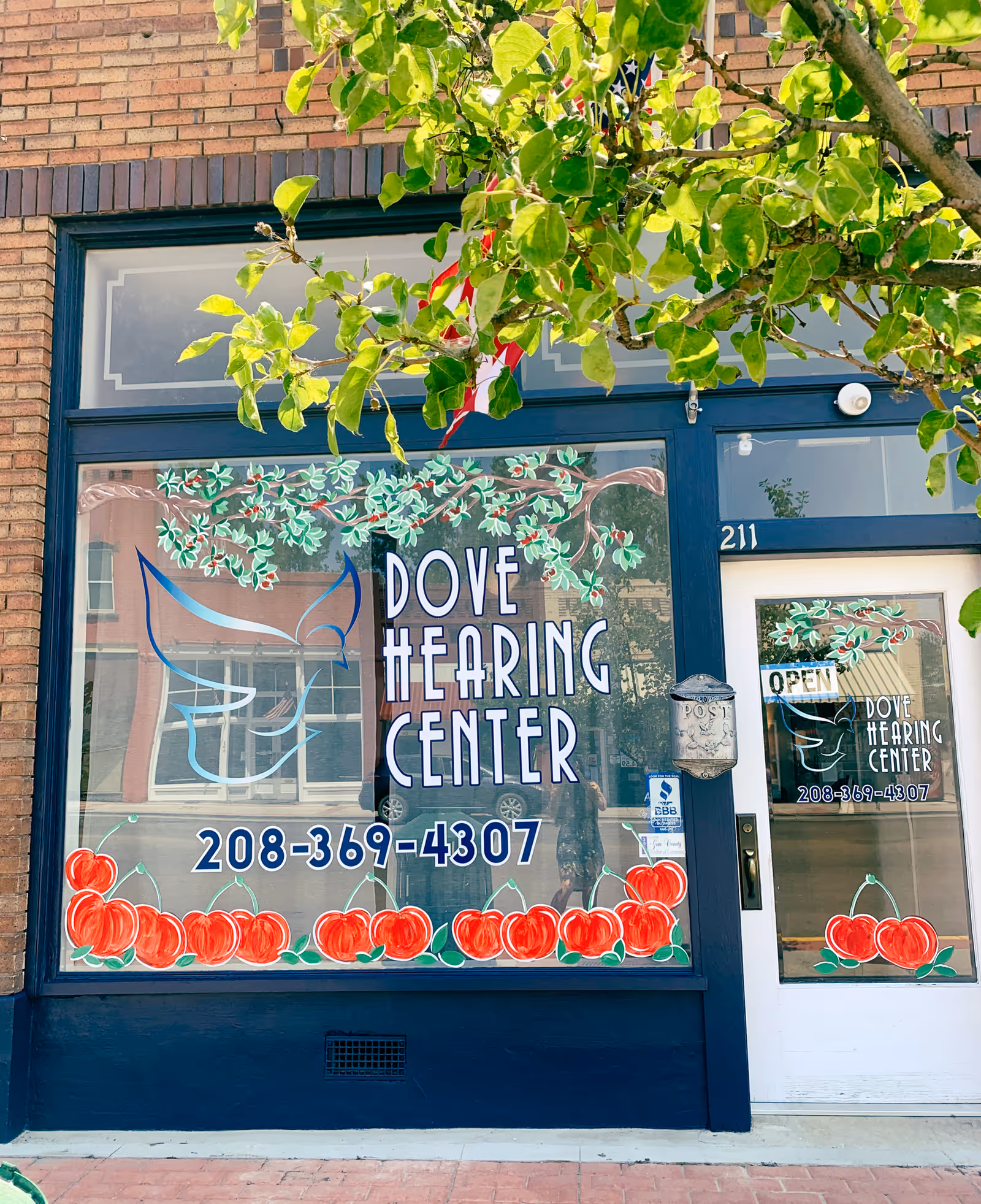 Brick storefront with large window sign reading Dove Hearing Center and phone number.