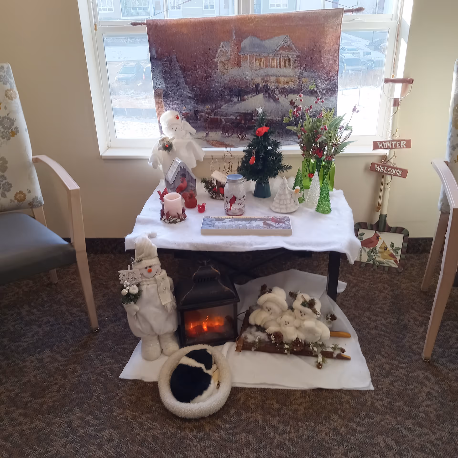 Winter holiday display on a table by a window with snowman and pine decorations