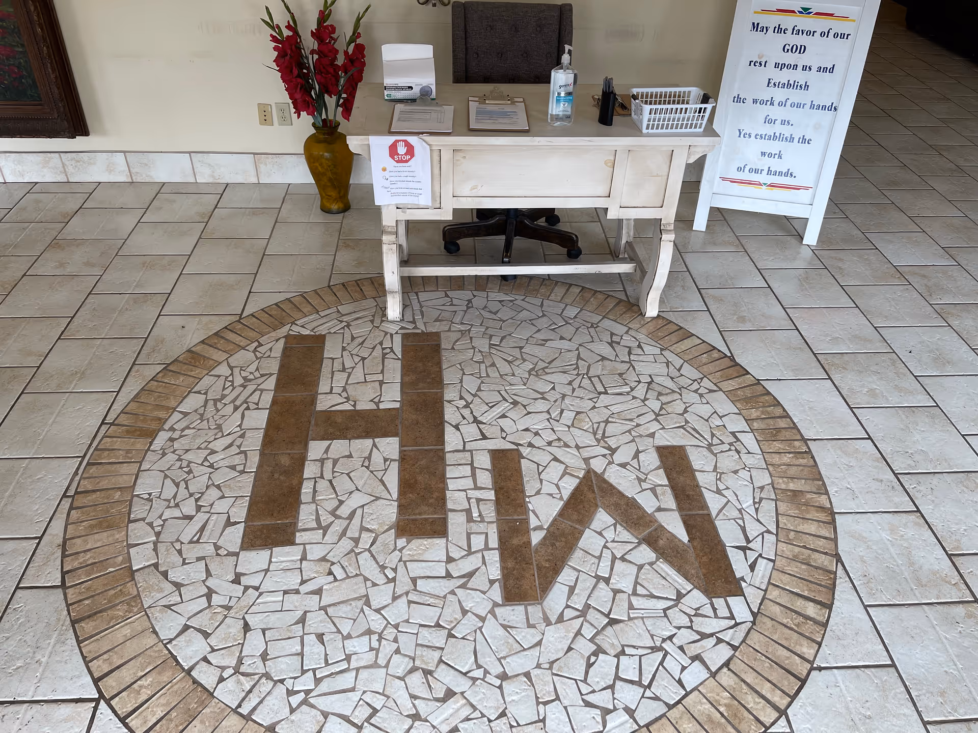 Inside a senior living lobby, a white desk sits on a circular mosaic tile floor.